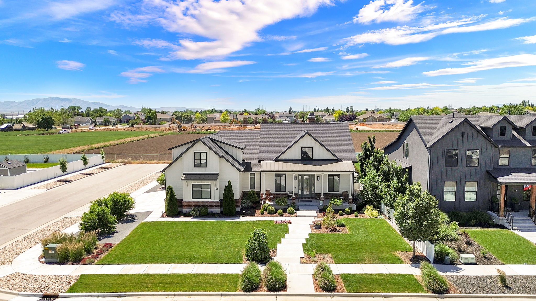 Modern farmhouse residence featuring a dark shingle roof, white siding, and brick accents