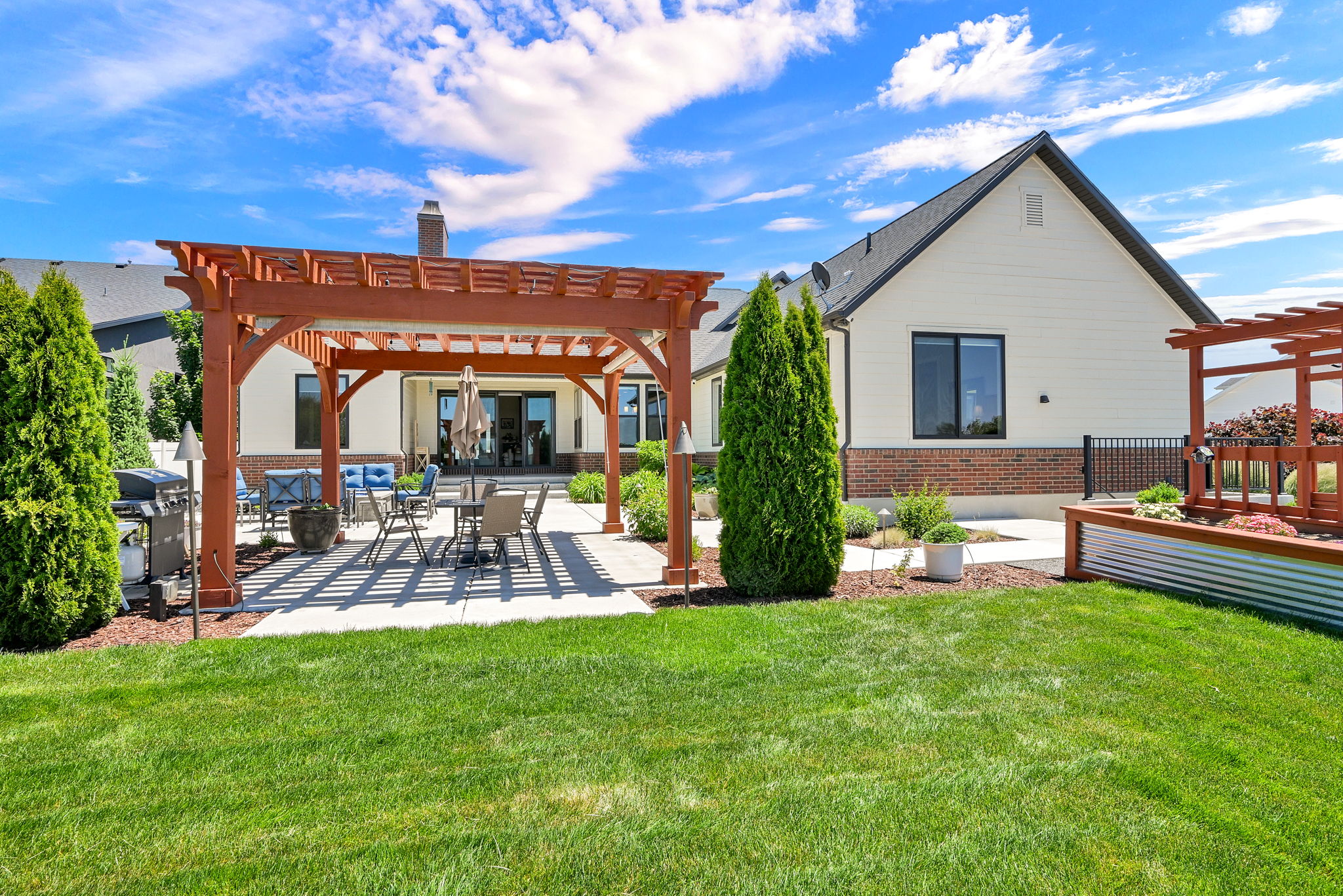 Expansive backyard featuring a lush lawn, concrete patio, and a wooden pergola