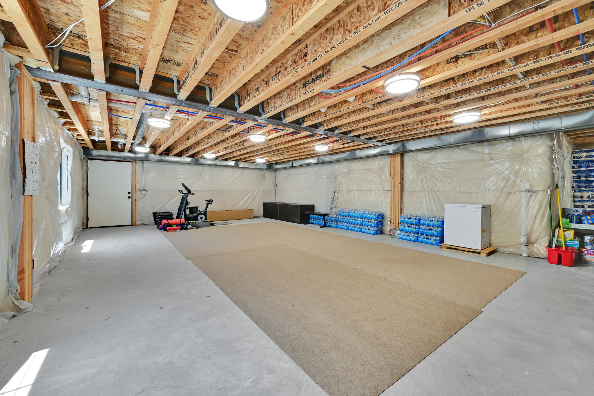 Expansive unfinished basement featuring concrete flooring and exposed ceiling joists