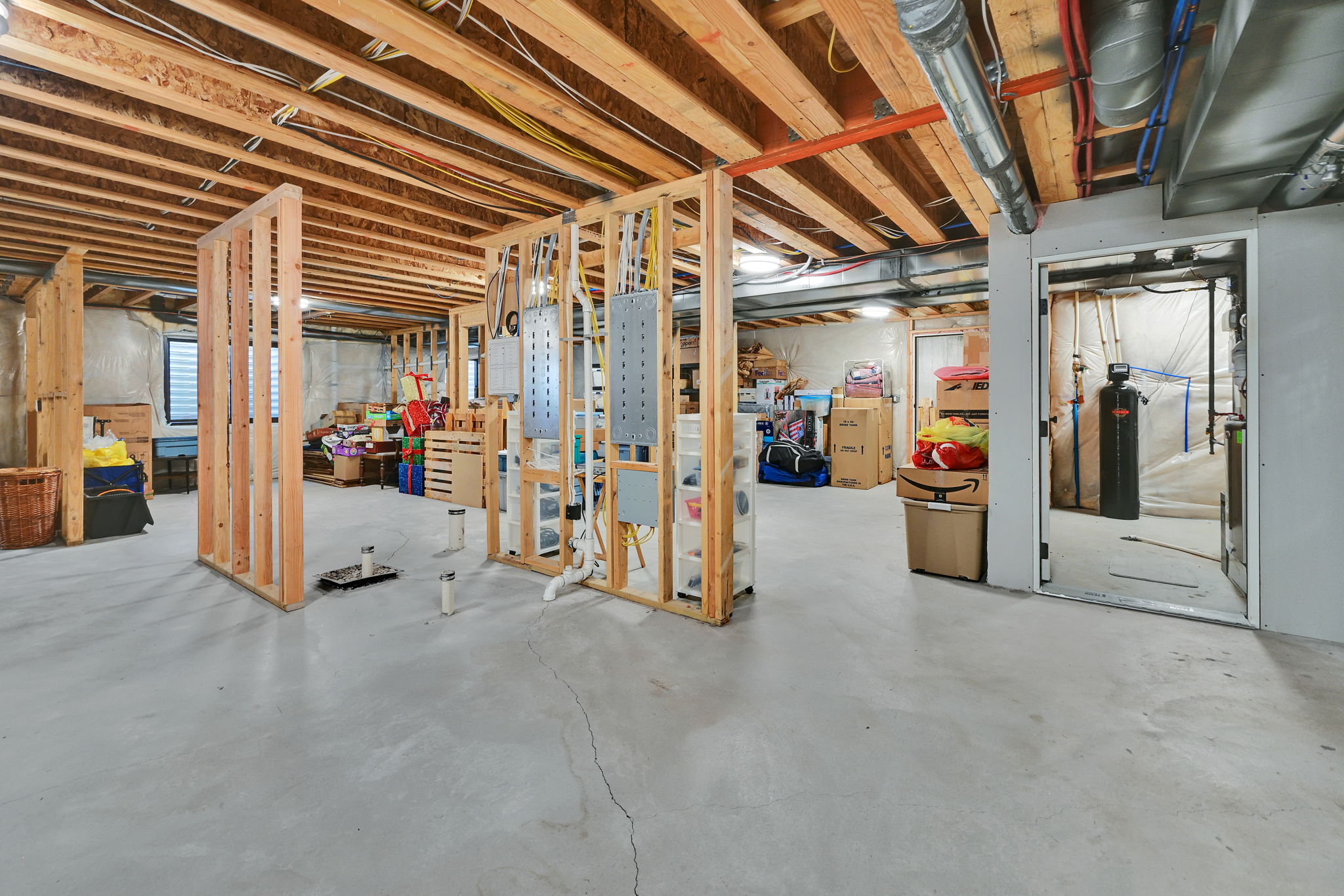 Unfinished basement with concrete flooring and exposed wood ceiling joists