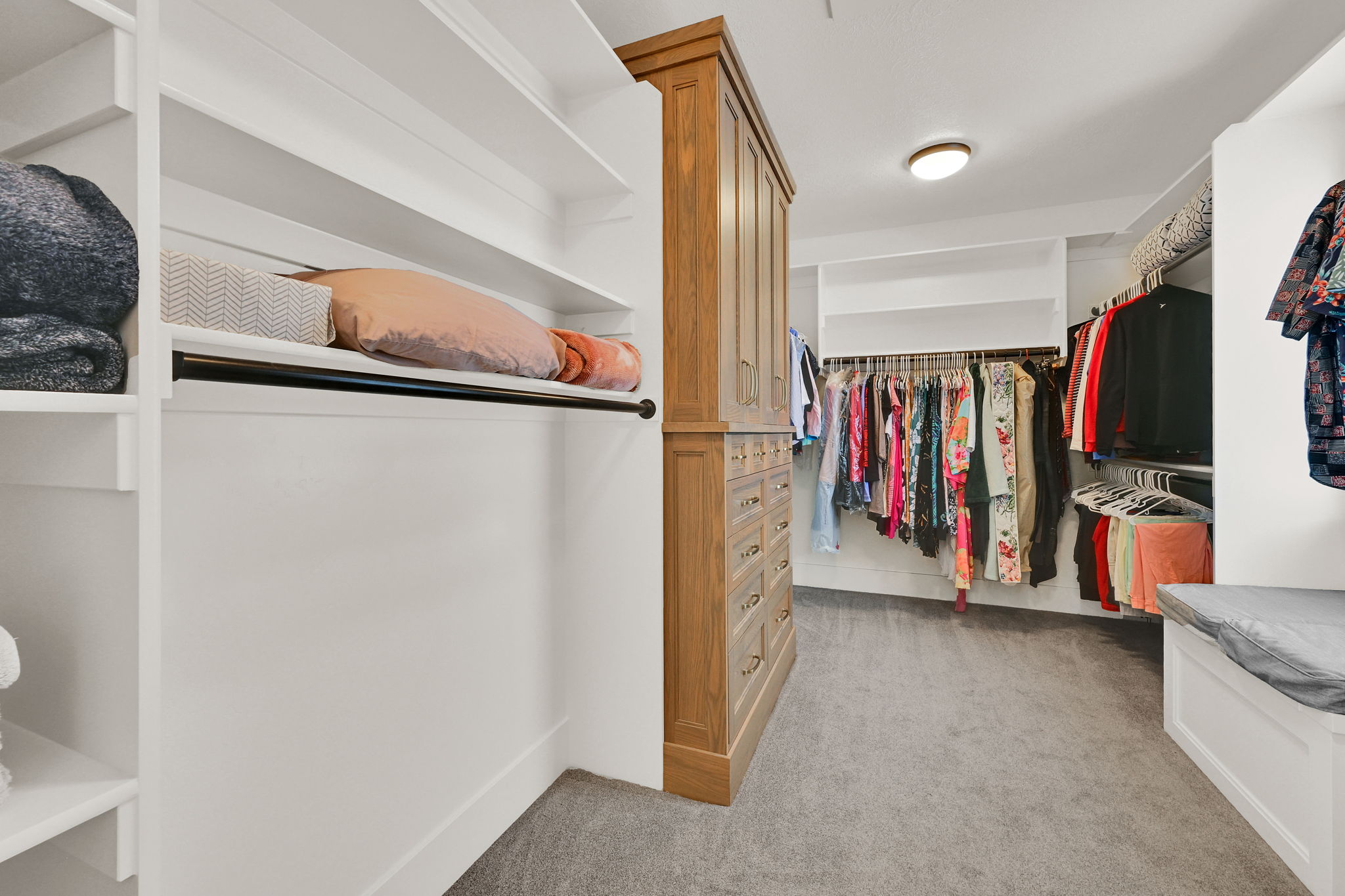 Custom closet system featuring built-in shelving, hanging rods, an integrated wood-finish cabinet with multiple drawers, and recessed lighting