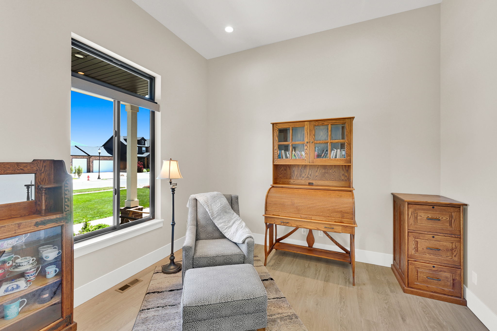 Tall window with white trim and black framing, light wood-finish flooring, recessed lighting, and neutral wall paint