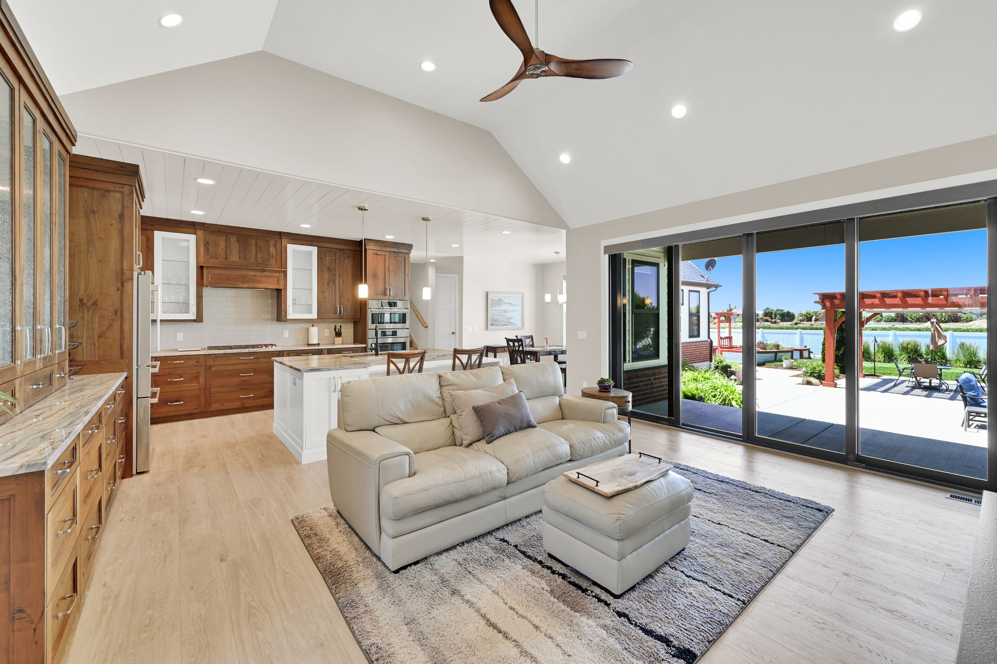Spacious open-concept living area featuring vaulted ceilings, wood-finish flooring, and a contemporary ceiling fan