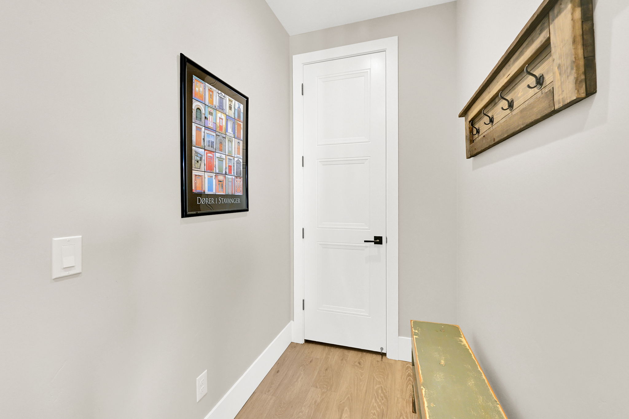 Interior hallway featuring light-toned walls, wood-finish flooring, and white baseboards