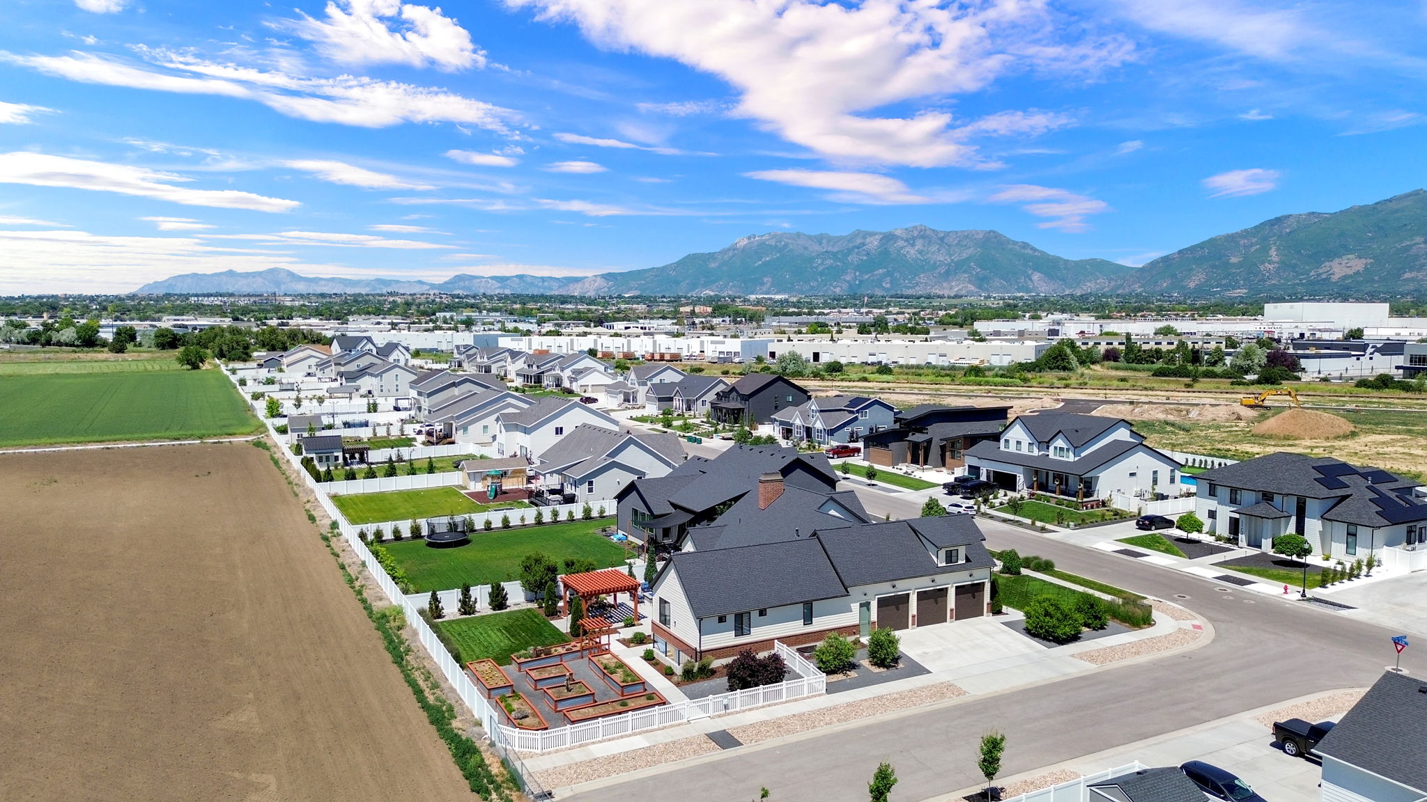 Expansive residential development with contemporary homes, mountain backdrop, and agricultural land