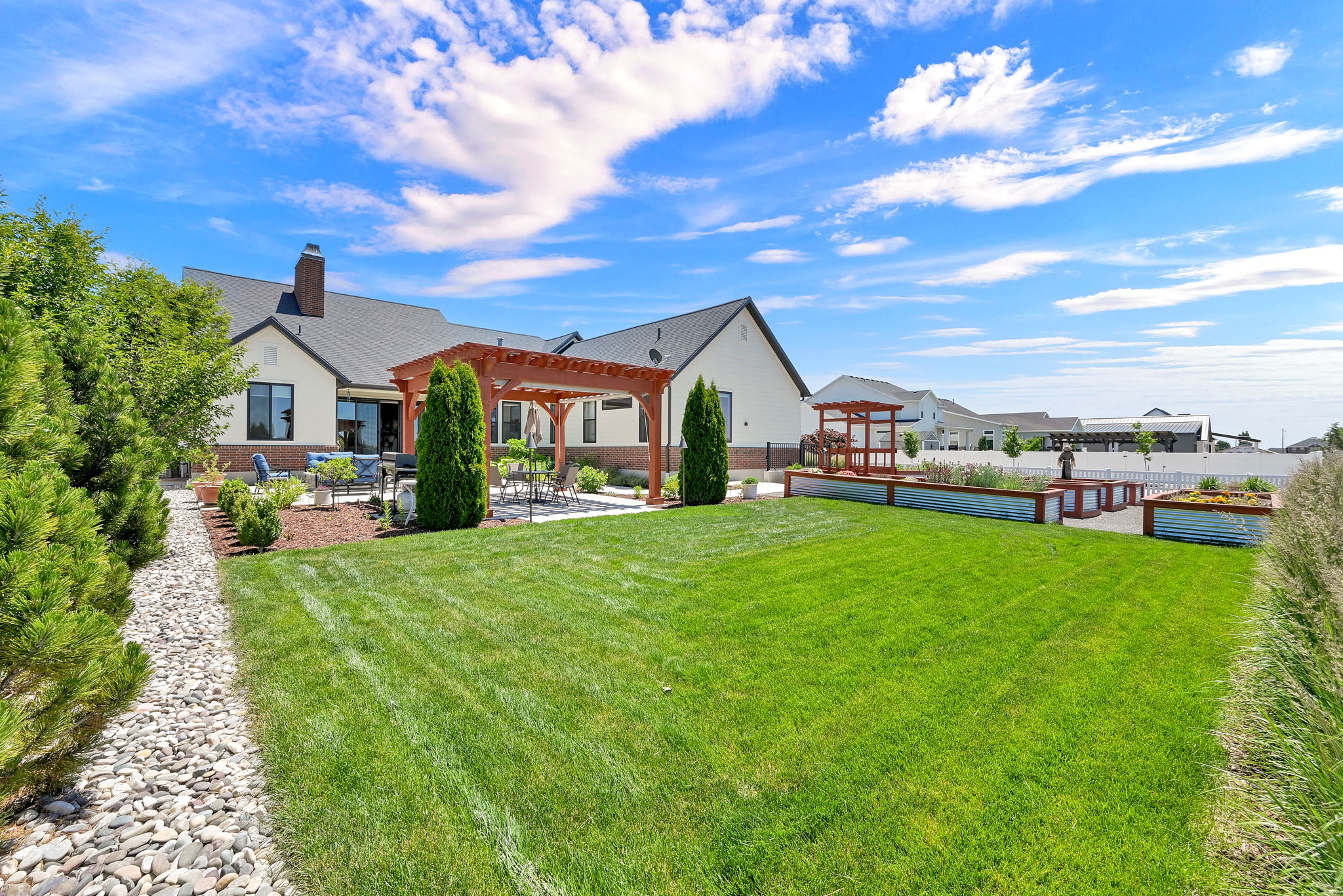 Expansive backyard featuring a manicured lawn, a large paver patio, and a wood pergola