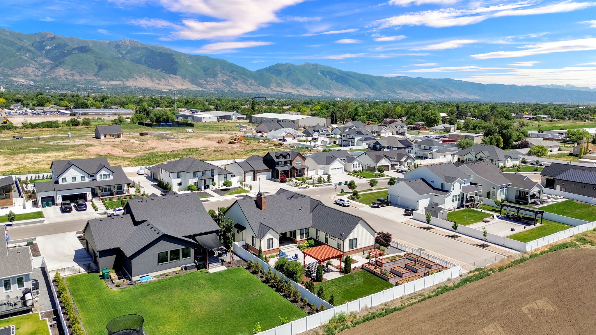 Aerial perspective showcasing a residential development with modern homes, mountain backdrop, and clear skies