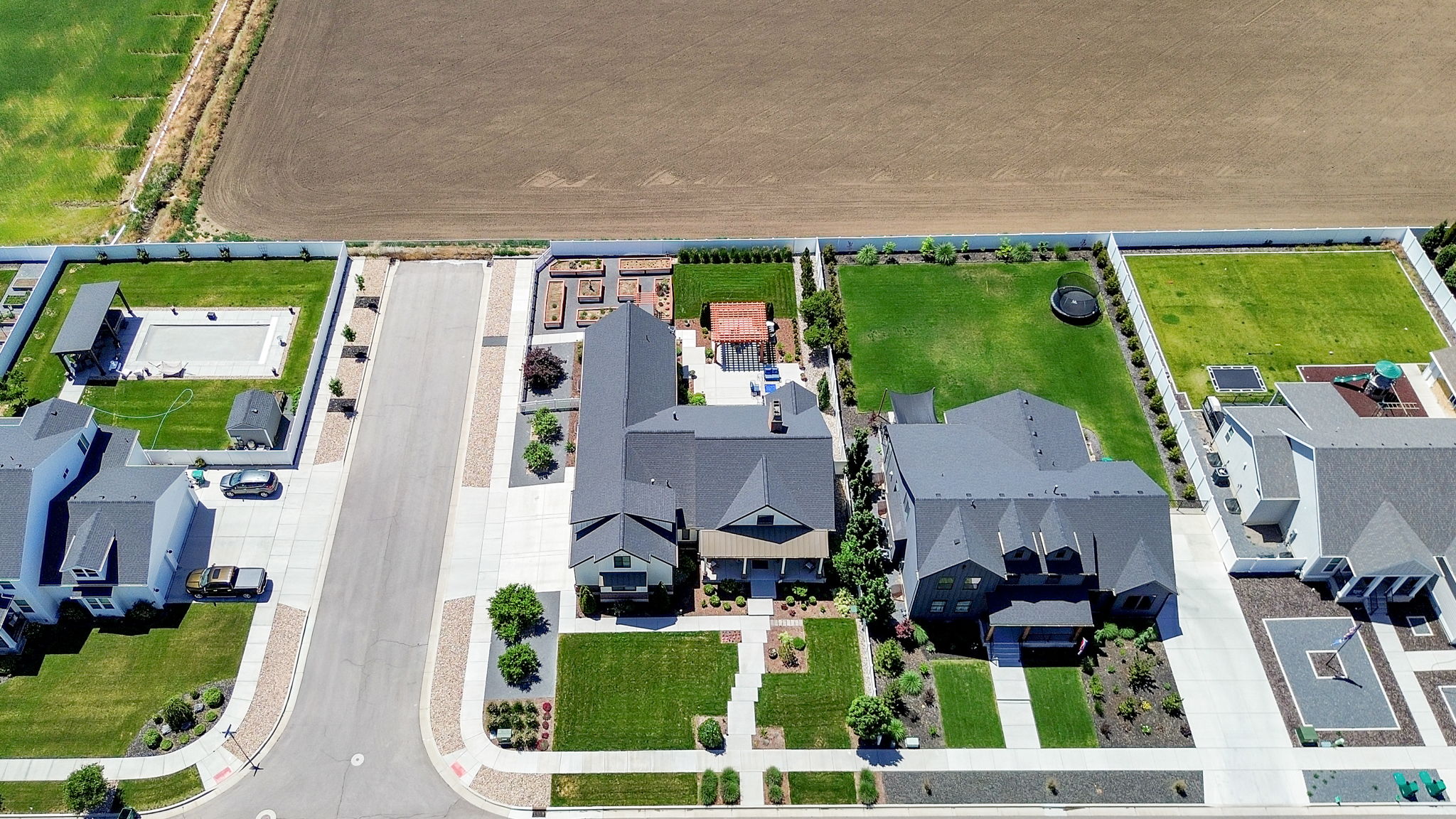 Aerial perspective showcasing a residential street with modern homes, manicured lawns, and substantial backyard spaces