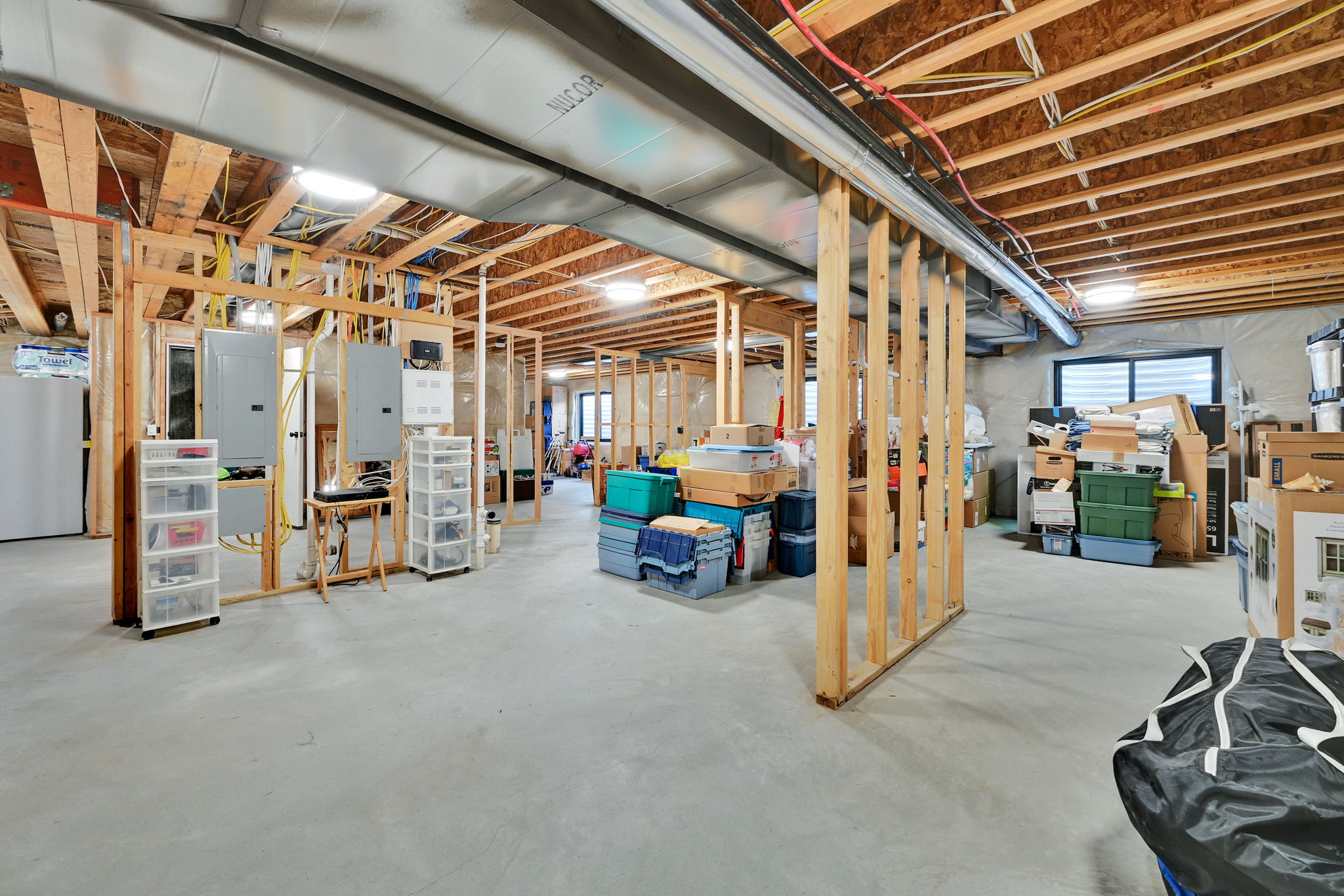 Unfinished lower level featuring concrete flooring, exposed ceiling joists, and framed partition walls