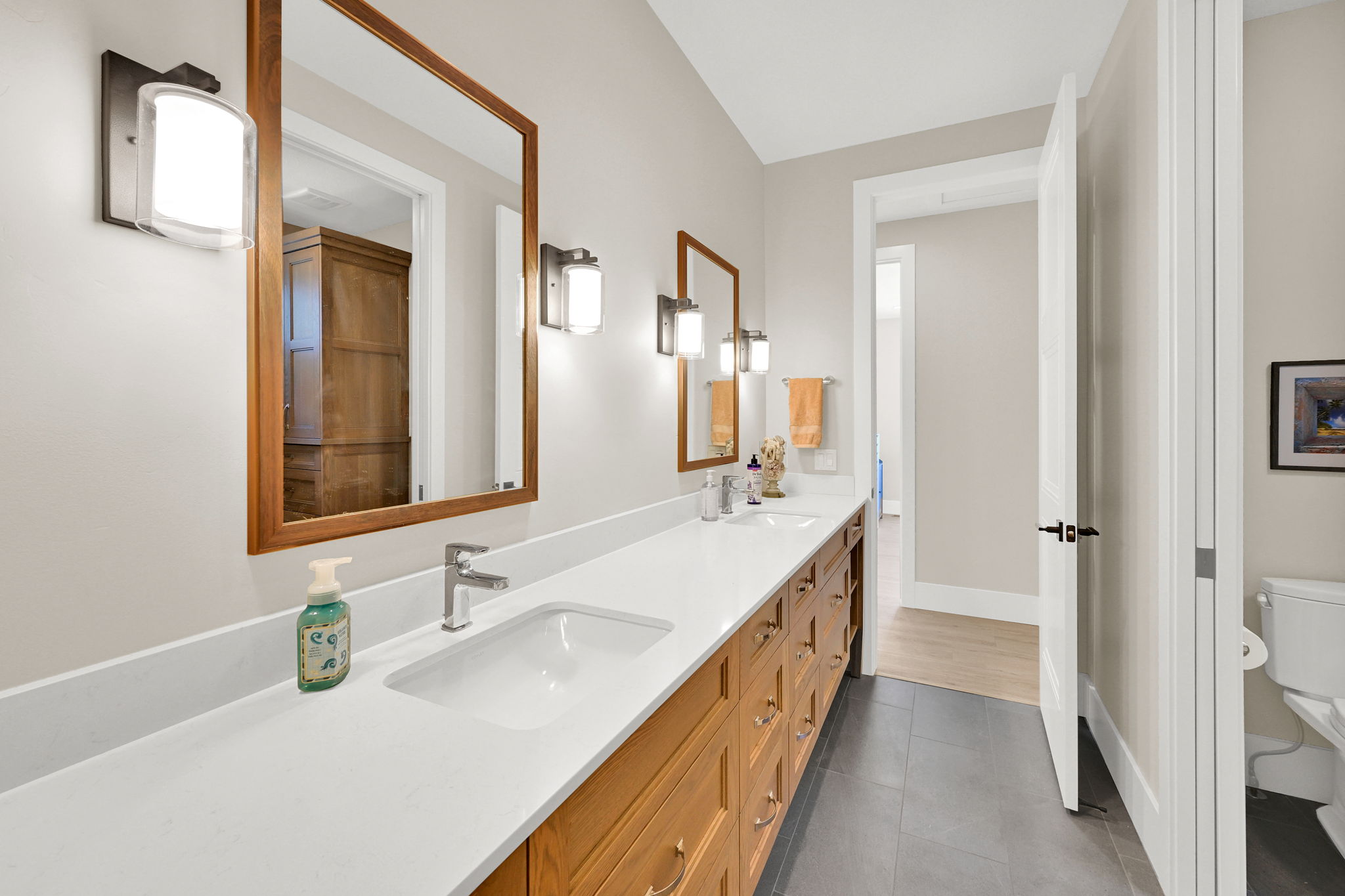 Double vanity with wood-finish cabinetry, white countertop, and integrated sinks