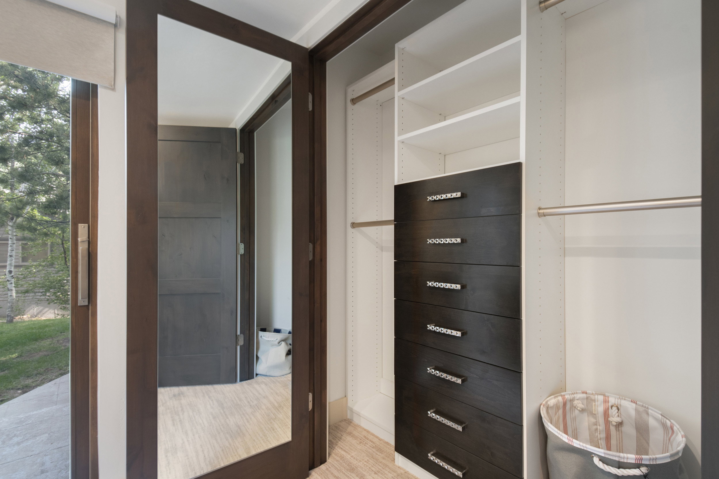 Custom closet system featuring white shelving and dark wood-finish drawers with polished hardware