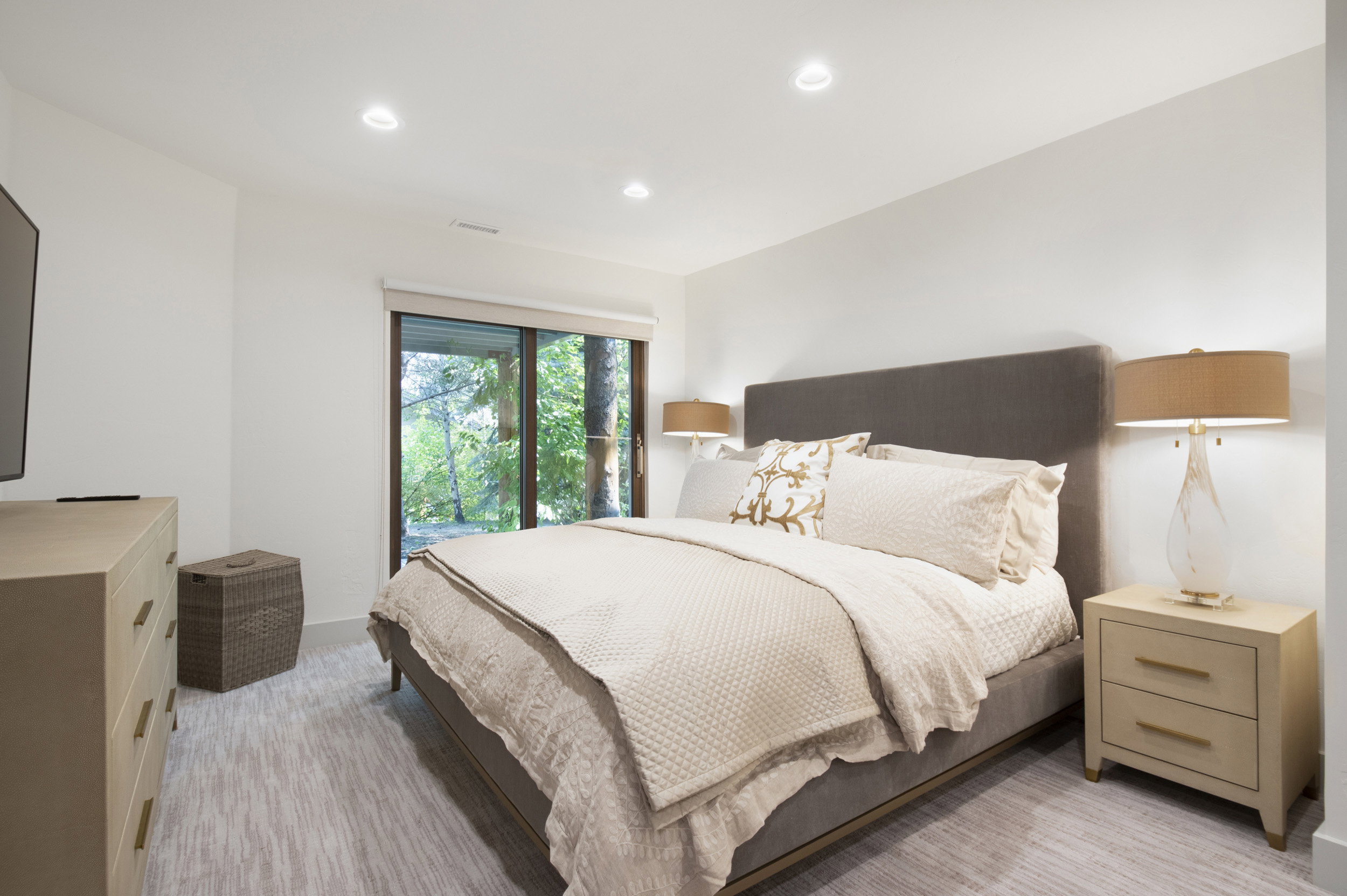 Bedroom featuring light-toned walls, recessed lighting, and a sliding glass door providing natural illumination