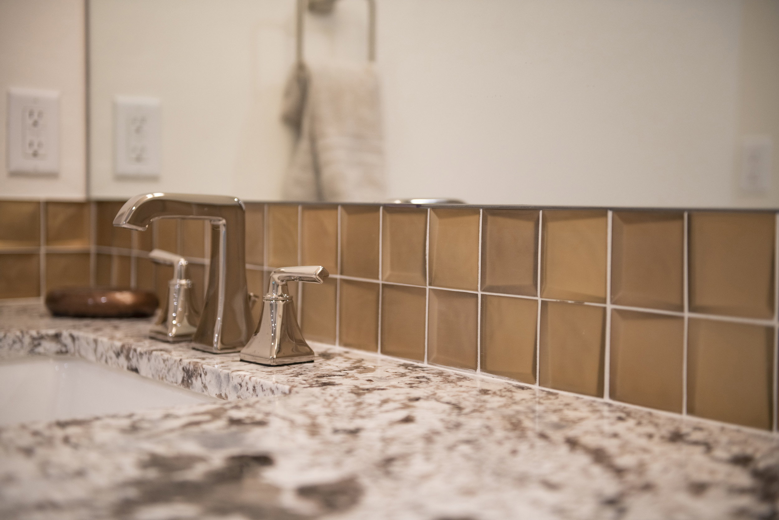 Polished chrome faucet with dual handles, set within a speckled countertop