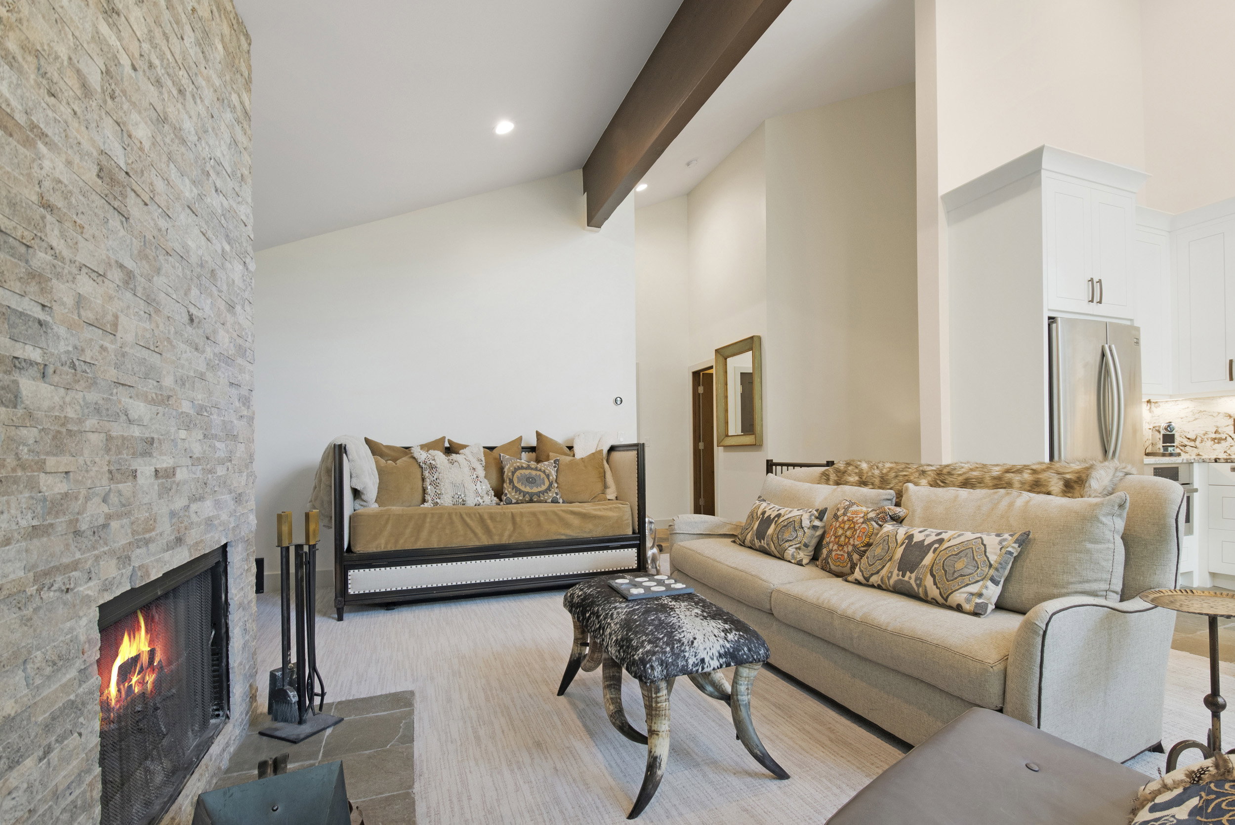 Stone-clad fireplace with slate hearth, vaulted ceilings, and exposed wood beam