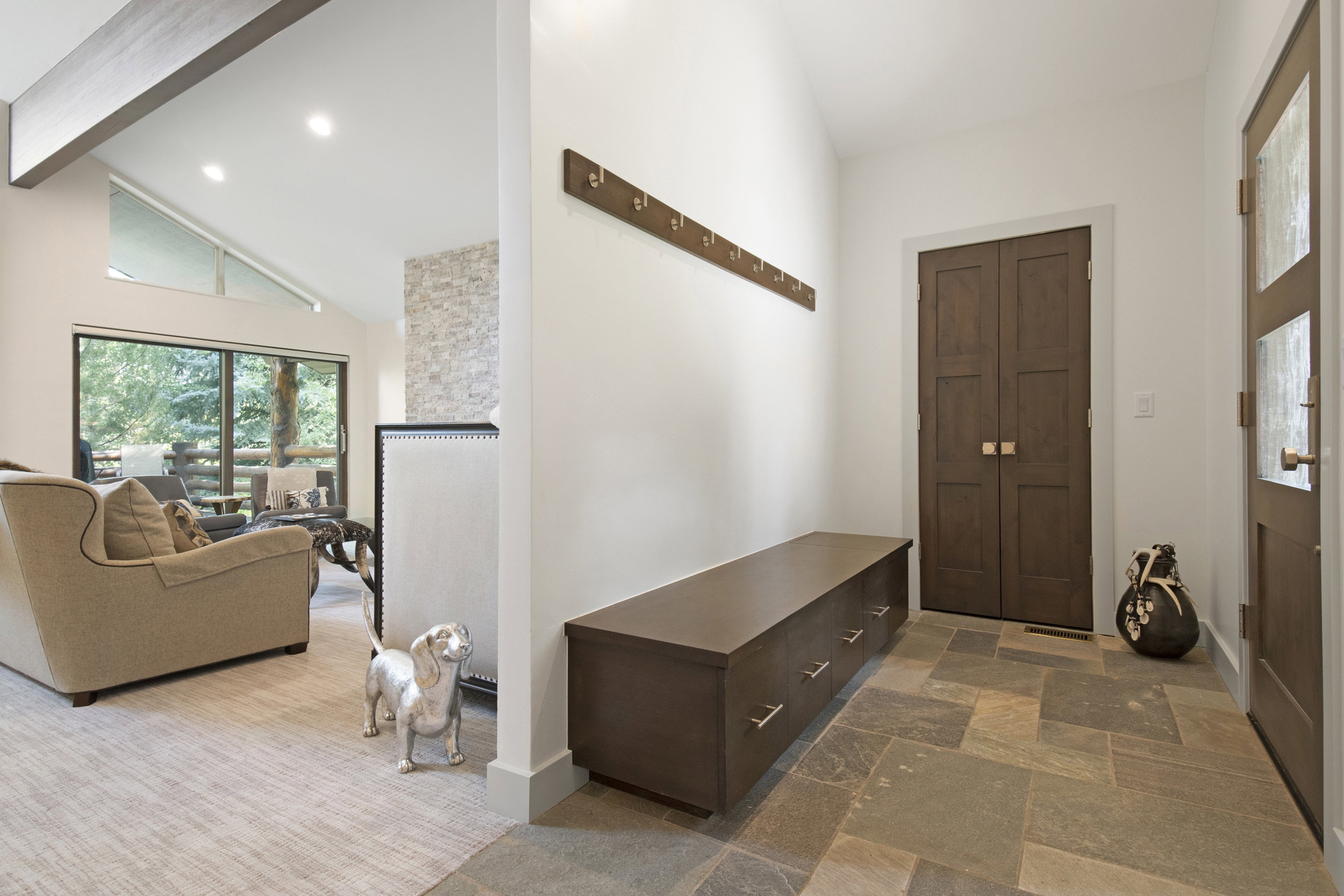 Entryway featuring natural stone tile flooring and a built-in storage bench