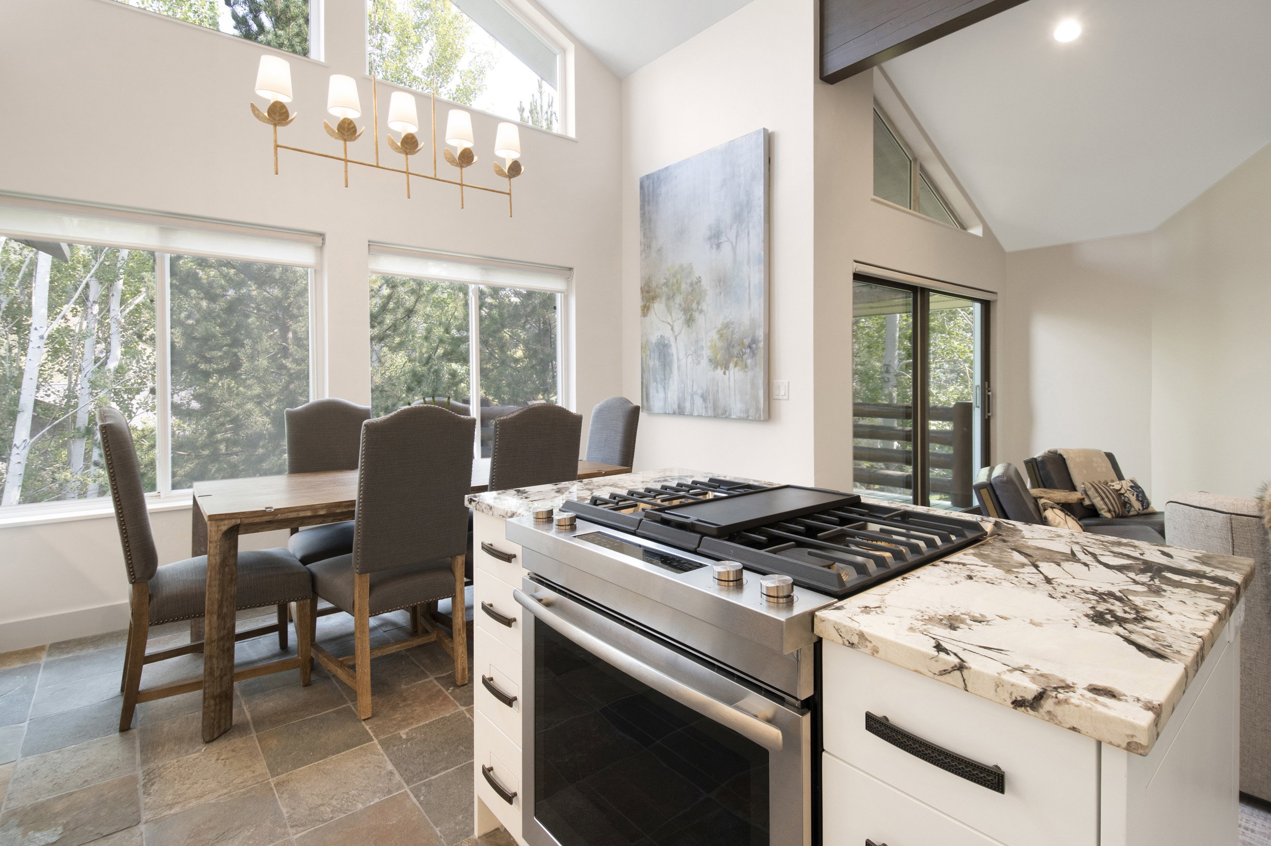 Open-concept dining space featuring high ceilings, a linear chandelier, and wide windows with exterior views