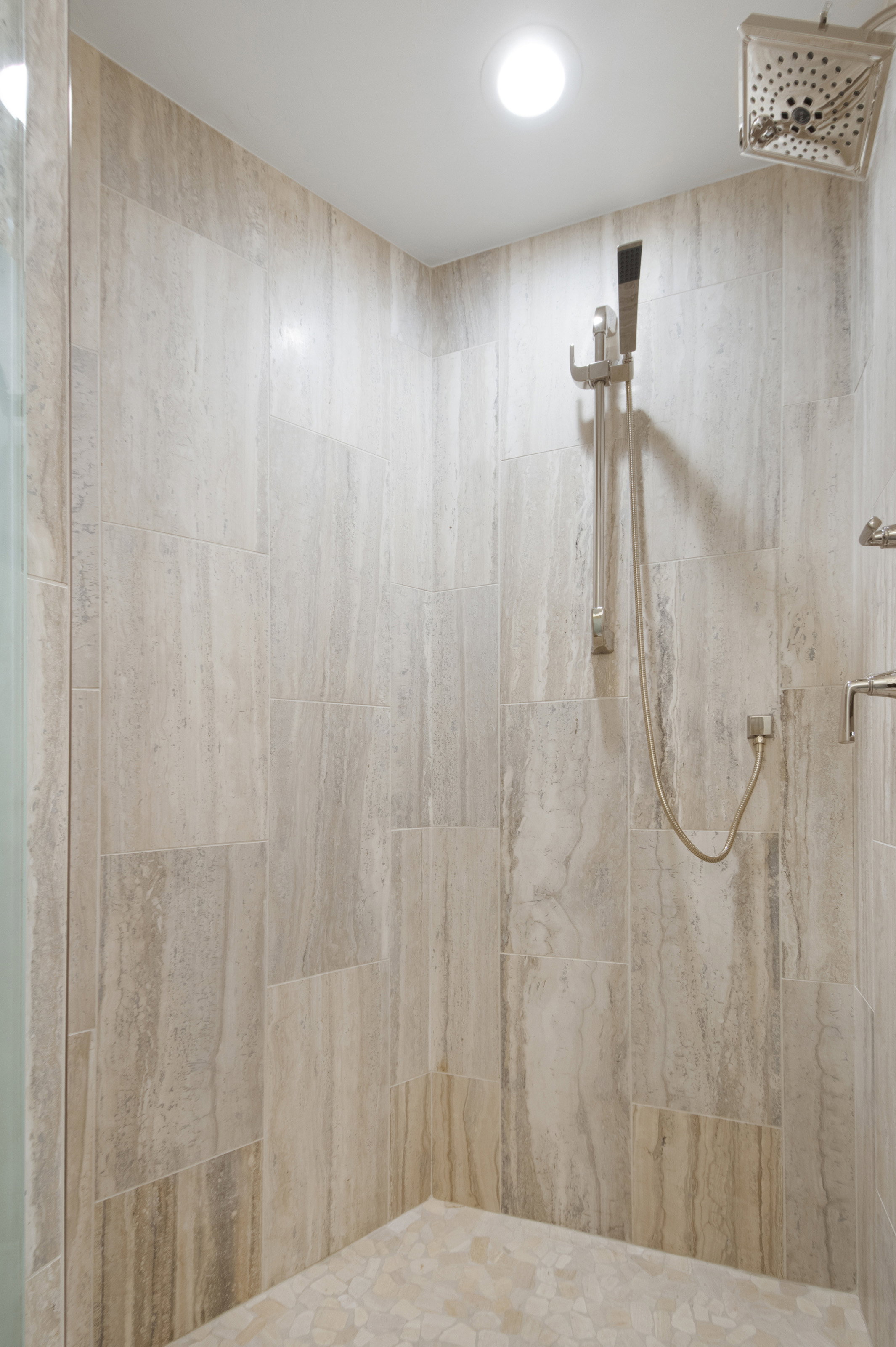 Tiled shower with a rain shower head, handheld shower, and recessed lighting