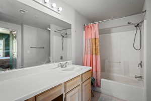 Bathroom featuring a single vanity with a white countertop, wood-finish cabinetry, an integrated sink, a large mirror, and a shower-bathtub combination with white subway tile surround