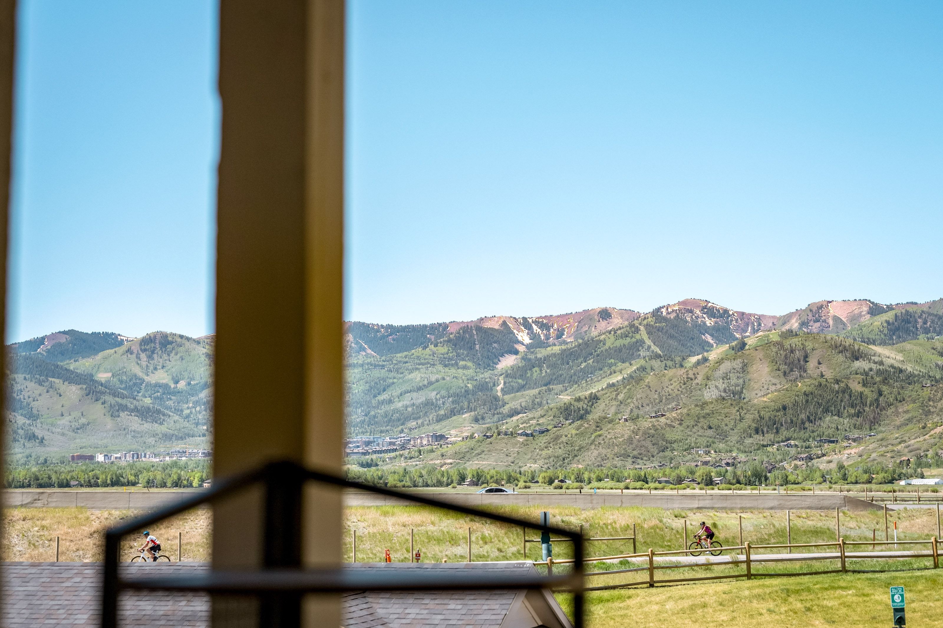 Expansive mountain landscape visible through a large window, featuring distant peaks with varied foliage