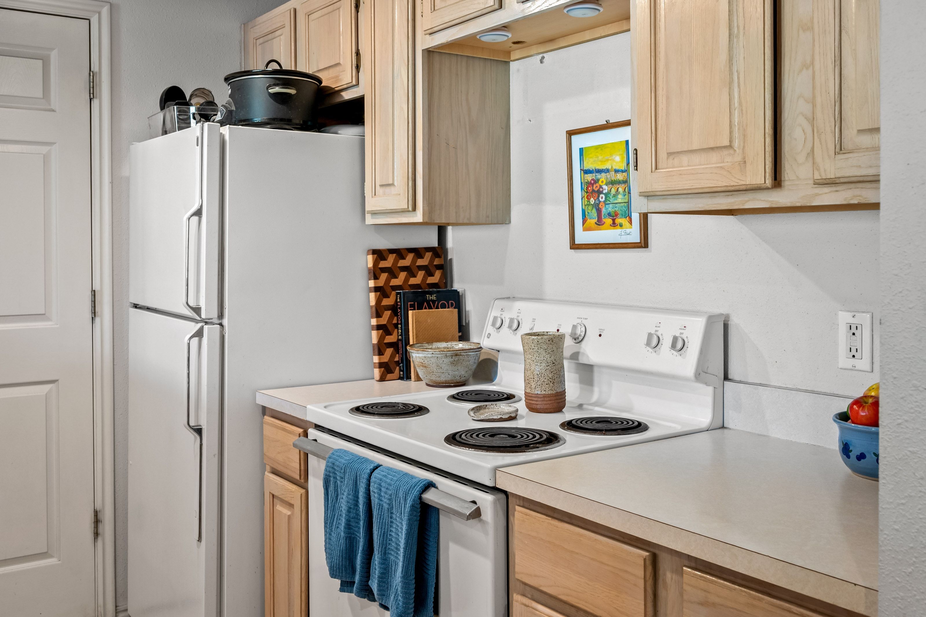 Kitchen featuring light wood cabinetry, white countertops, and a white electric range