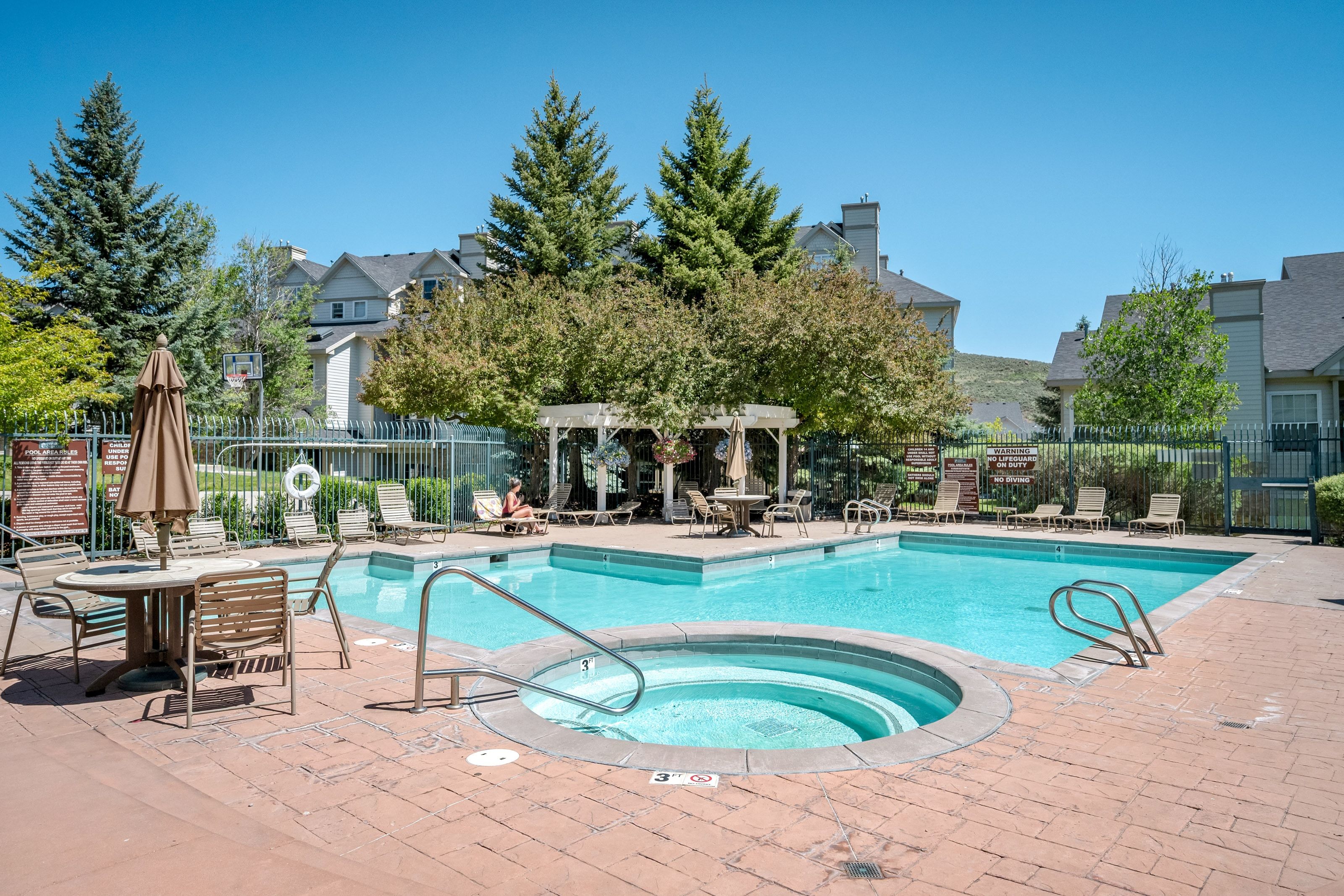 Outdoor swimming pool with integrated spa and surrounding brick paver deck