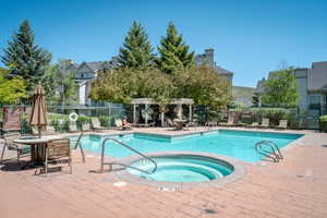 Outdoor swimming pool with integrated spa and surrounding brick paver deck
