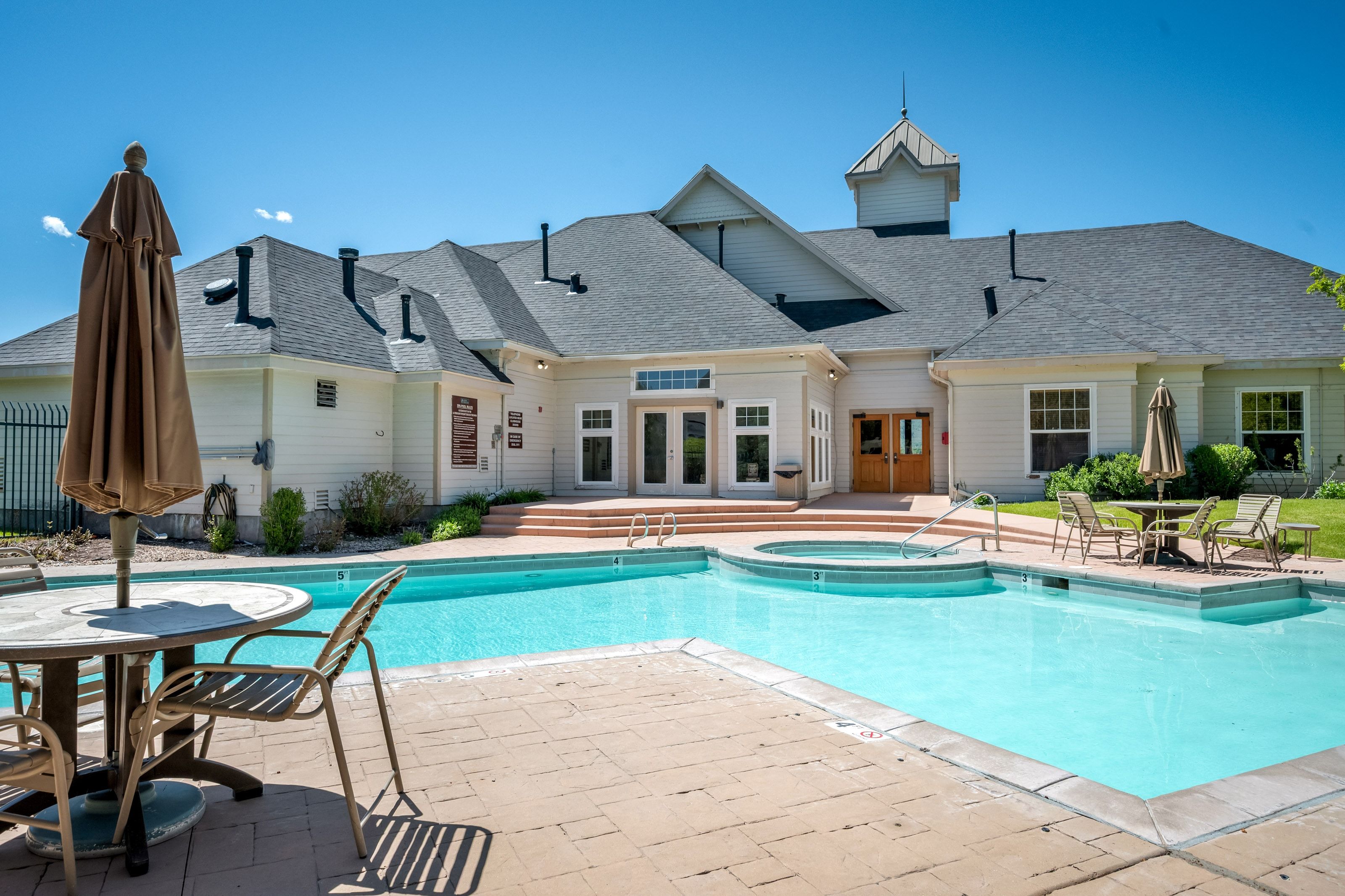 Outdoor swimming pool with integrated spa and surrounding paver patio