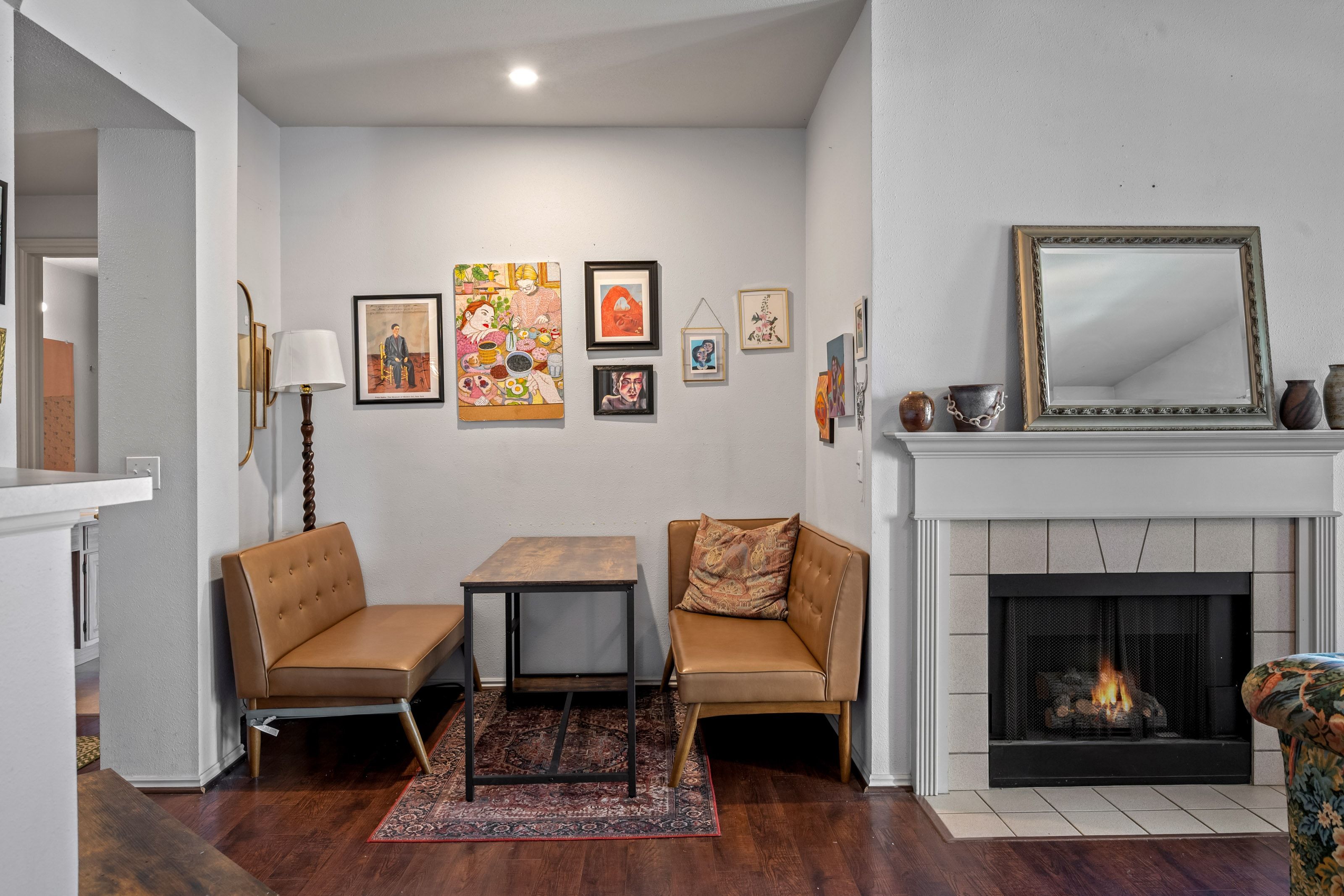 Living area featuring rich wood-finish flooring, a contemporary fireplace with a tiled surround and white mantel, and recessed lighting