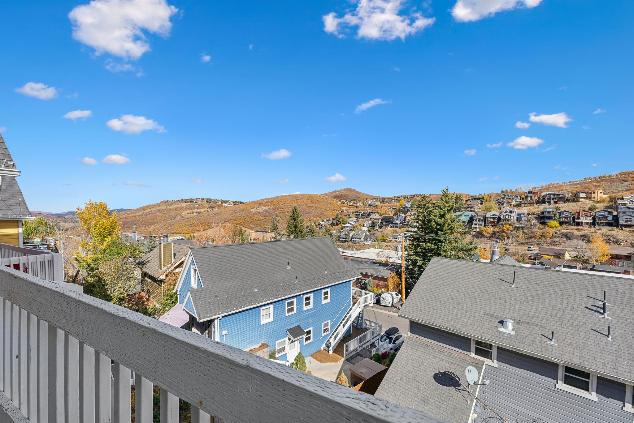 White railing providing an elevated perspective of the surrounding residential area and distant hills