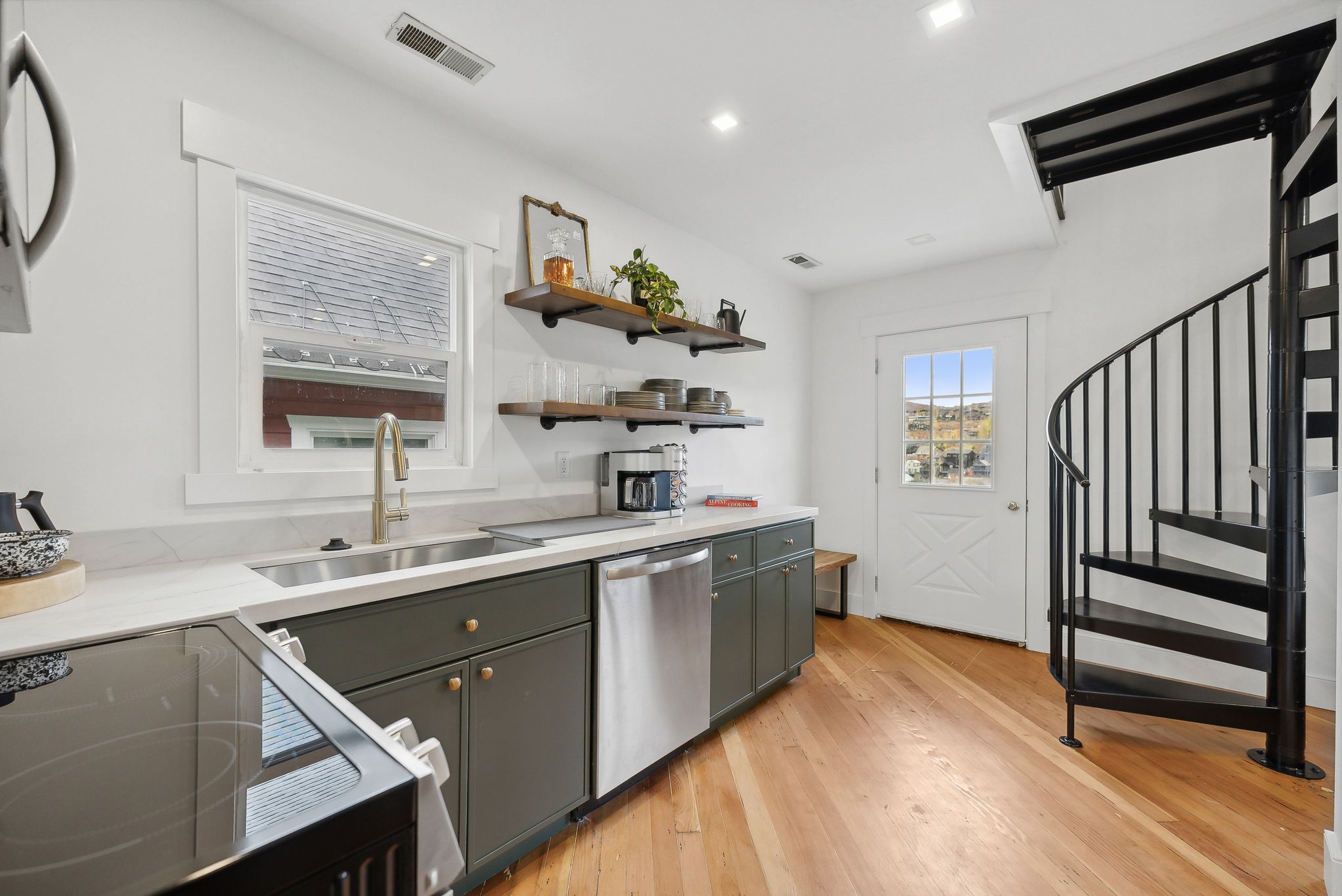 Kitchenette featuring a black metal spiral staircase, wood-finish flooring, and a white paneled door with glass inserts