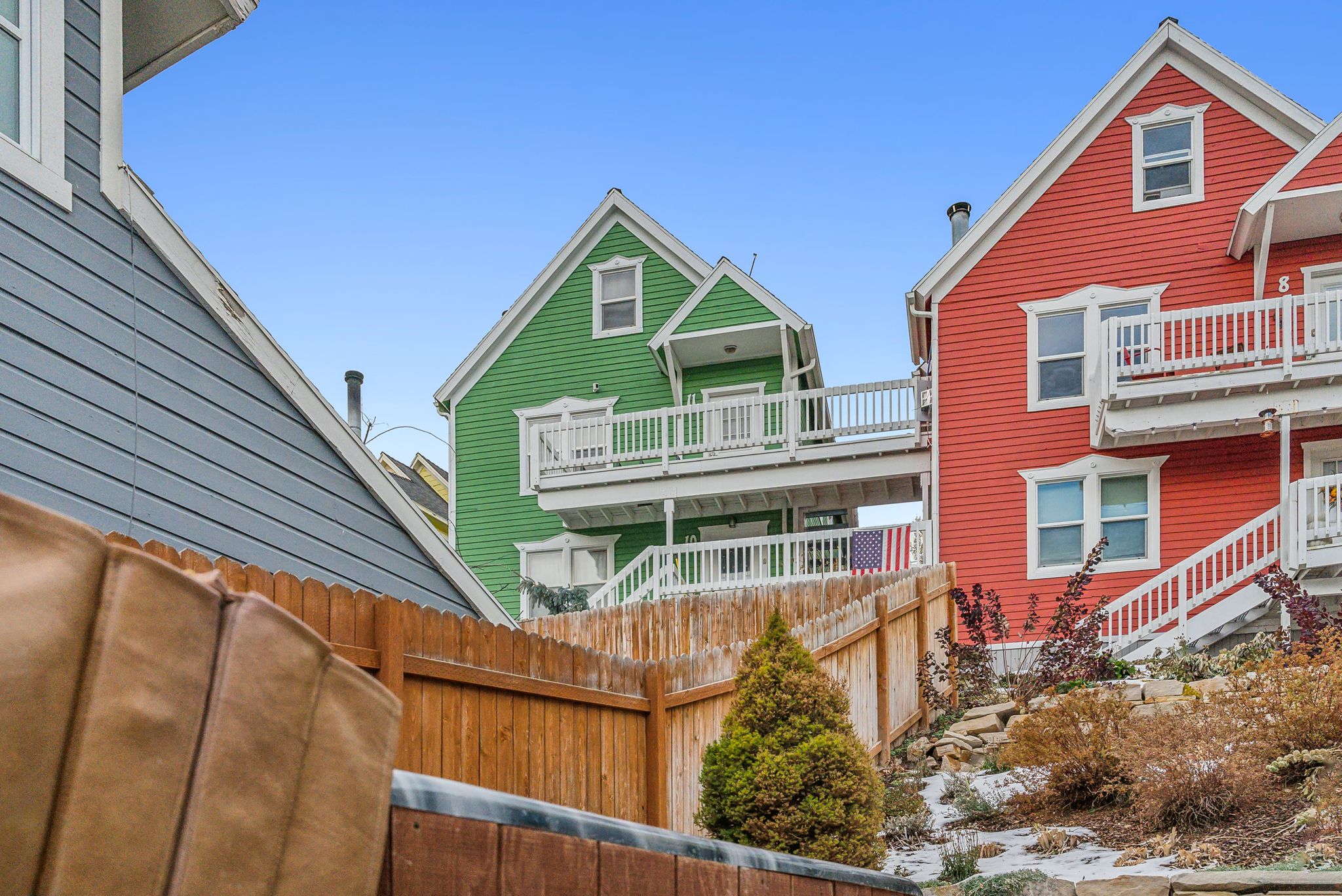 Multi-level residences featuring vibrant siding, white trim, and expansive outdoor decks with white railings