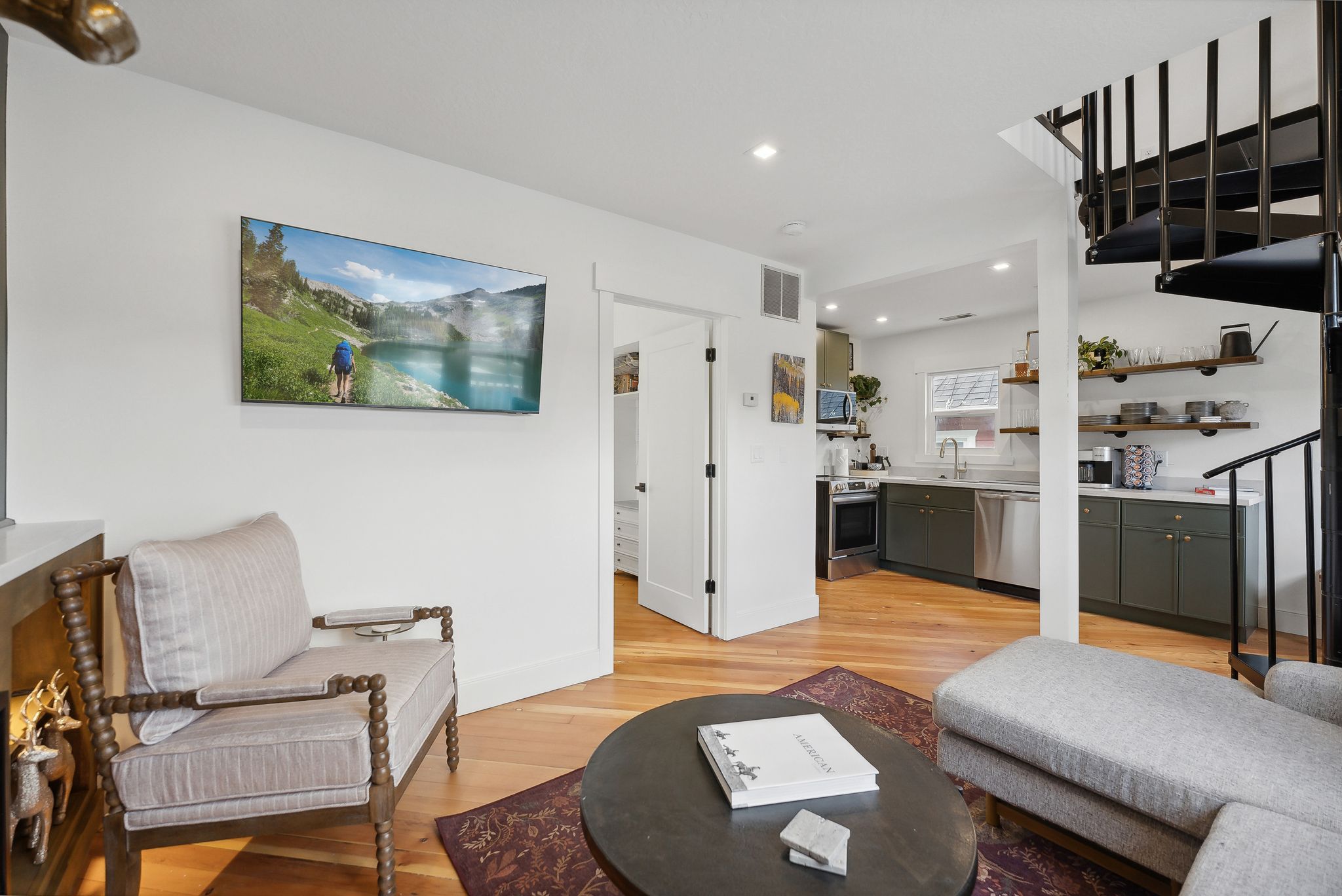 Open-concept living area featuring wood-finish flooring, recessed lighting, and a black spiral staircase