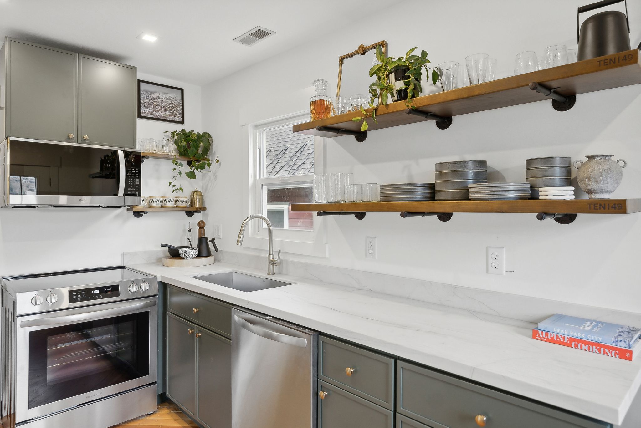 Kitchen featuring stainless steel appliances, open wood-finish shelving, gray cabinetry, and light countertops