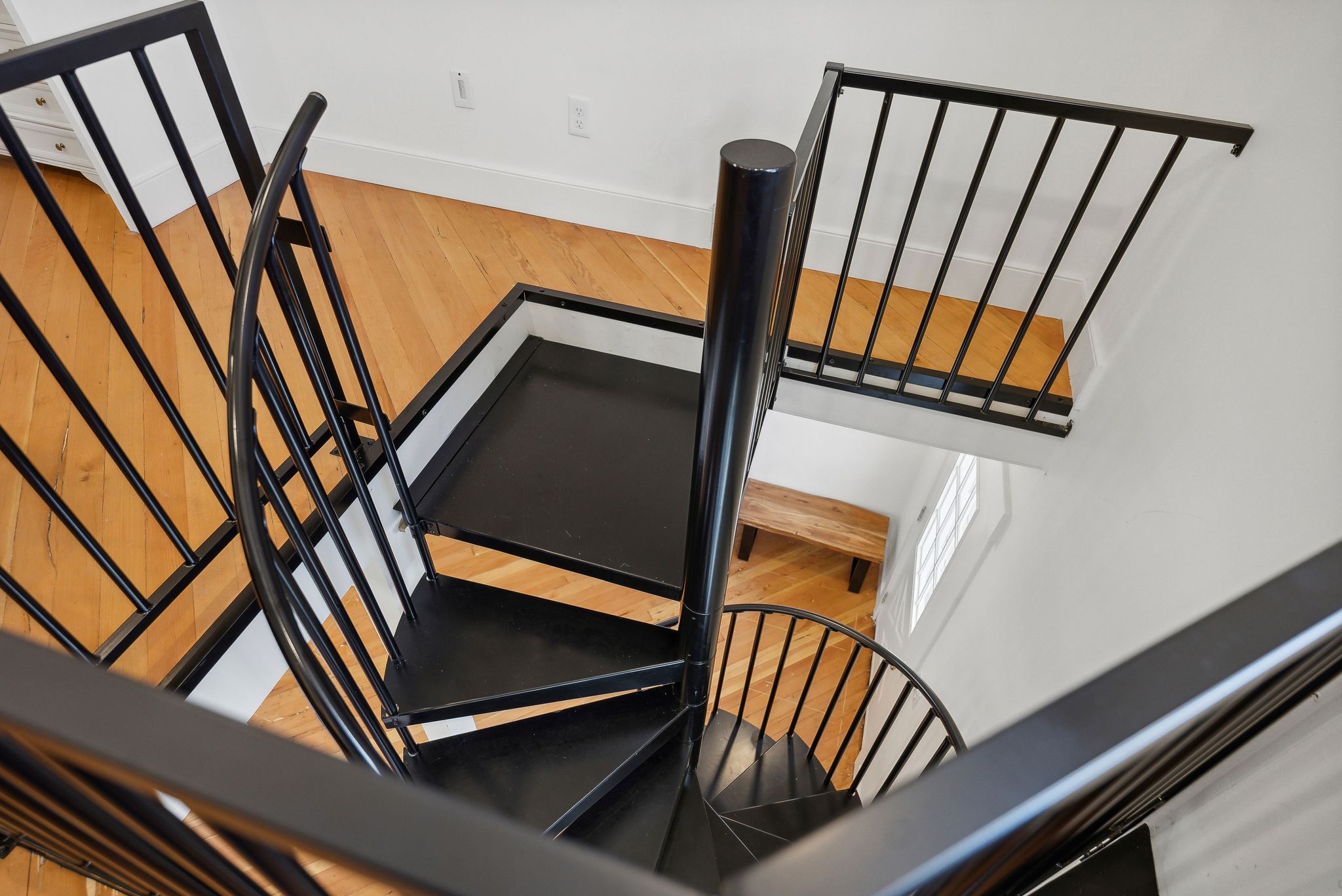 Black spiral staircase featuring metal railings, solid treads, and a central support column