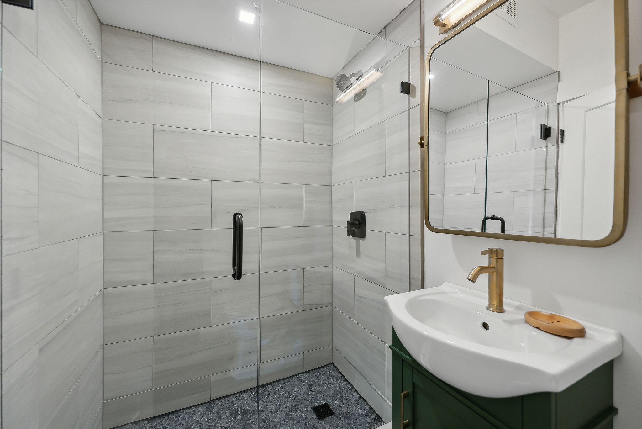 Bathroom featuring a glass-enclosed shower with large format tile, a dark gray tiled shower floor, and matte black shower fixtures