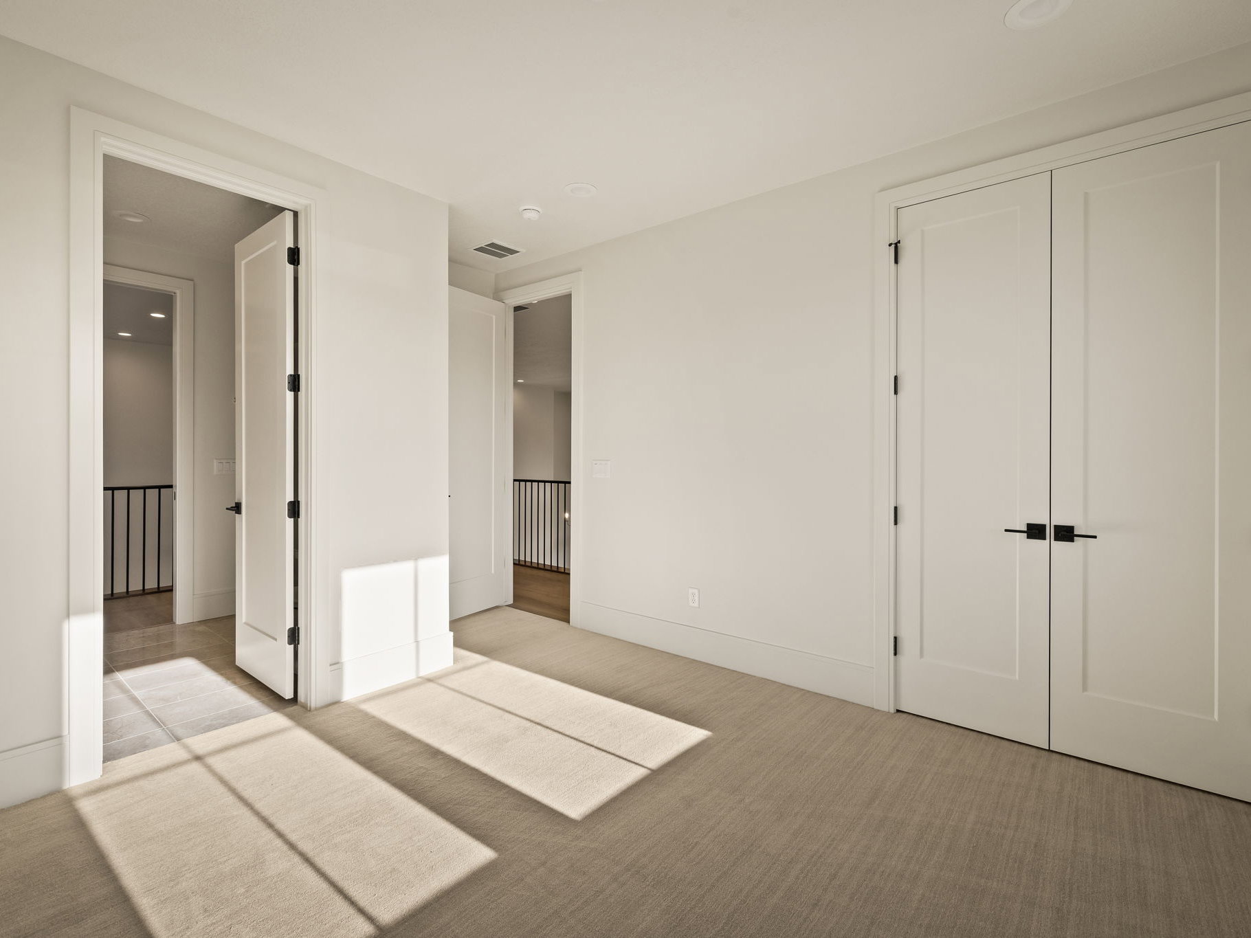 Neutral tone carpeted room with white walls, baseboards, and door frames