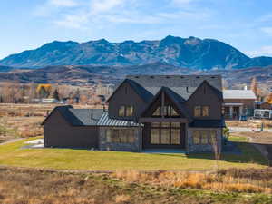 Contemporary two-story residence featuring a dark vertical board-and-batten siding facade and a stone-clad foundation