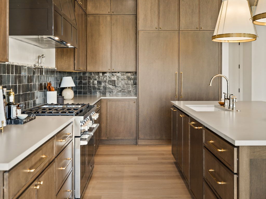 Gourmet kitchen featuring a stainless steel range, custom range hood, wood-finish flooring, recessed lighting, and a kitchen island with an integrated sink and pendant lighting