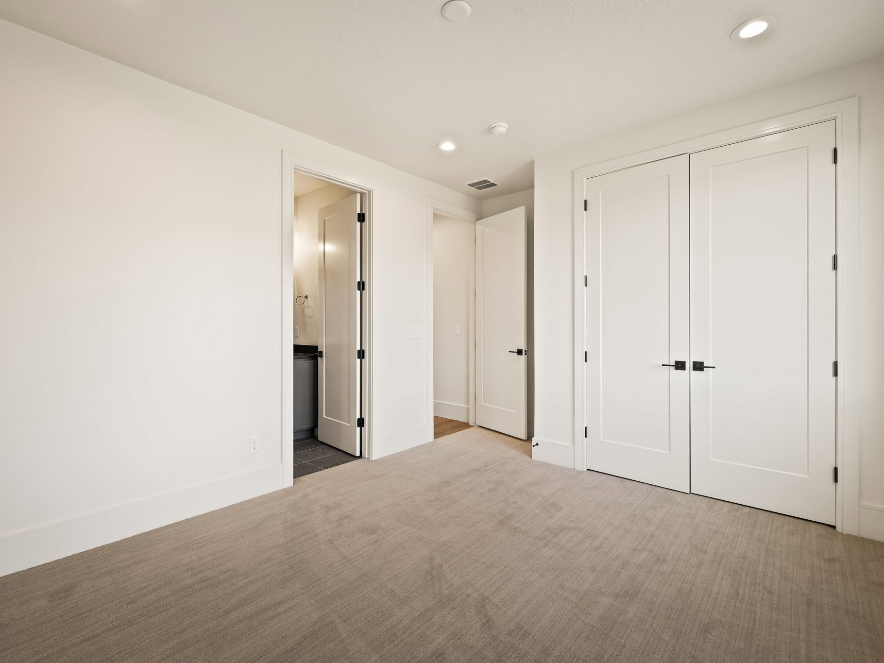 Neutral tone carpeted flooring with white baseboards