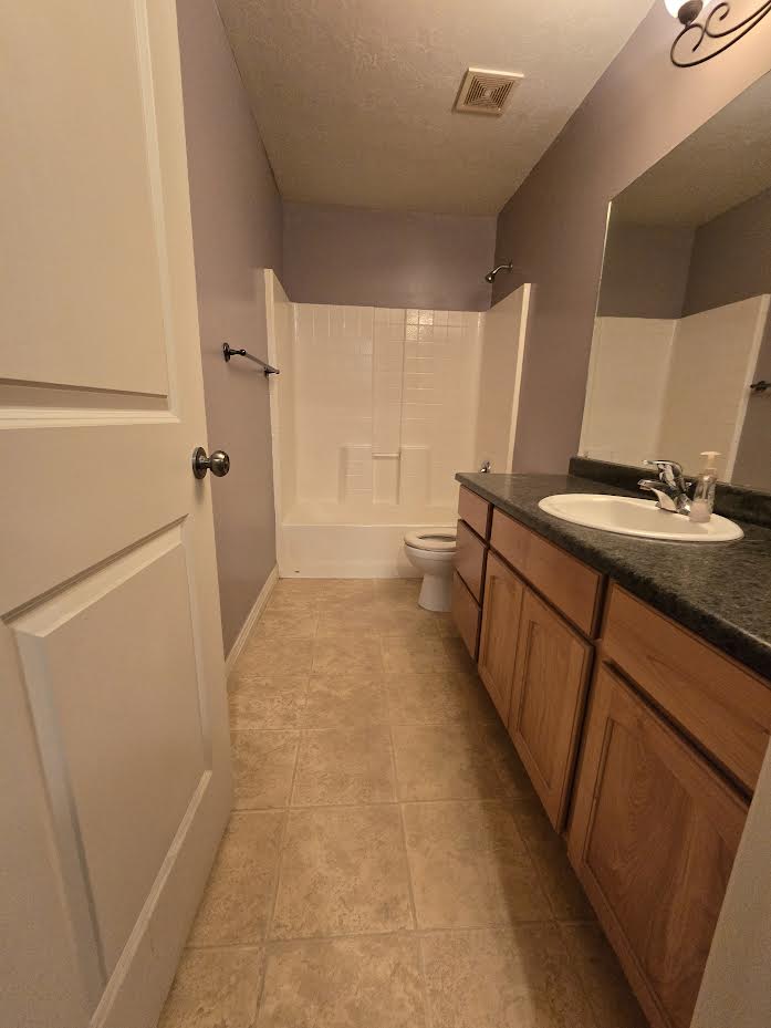 Bathroom featuring a vanity with wood-finish cabinetry, a dark countertop, and an integrated sink basin