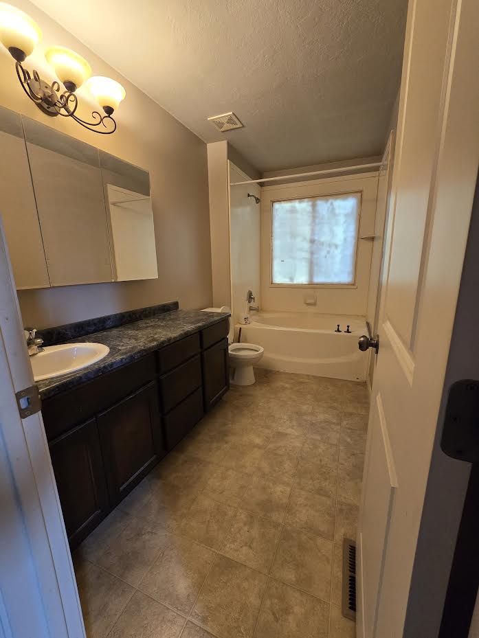 Bathroom featuring a dark wood-finish vanity with a single basin sink and a stone-look countertop