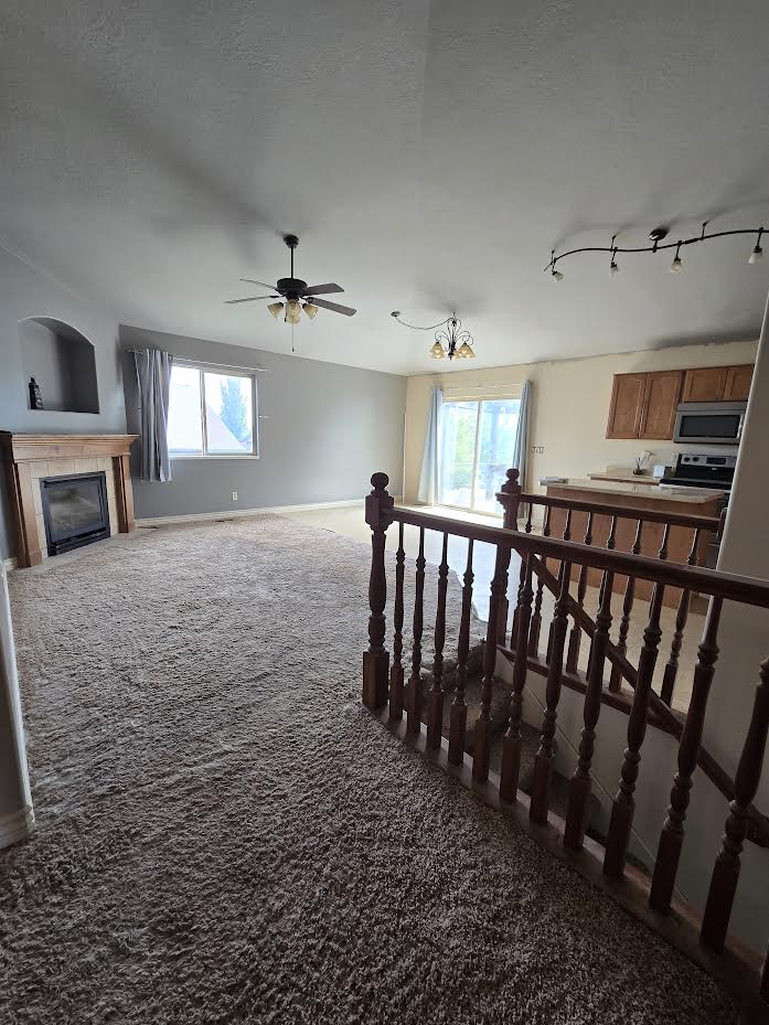 Expansive living area featuring plush carpeting and a gas fireplace with a wooden mantel
