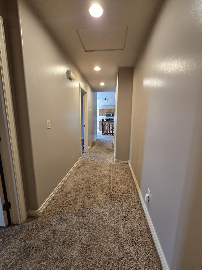 Carpeted hallway featuring recessed lighting and neutral wall tones