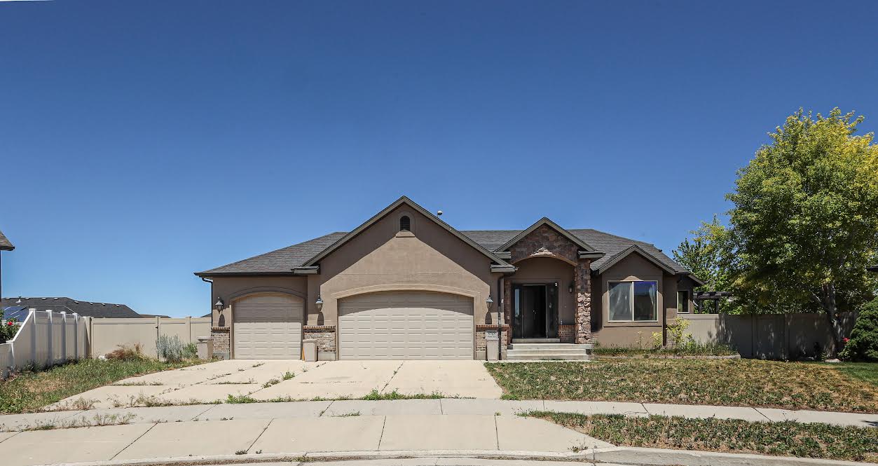 Stucco exterior with stone accents, a dual garage, and a covered entry