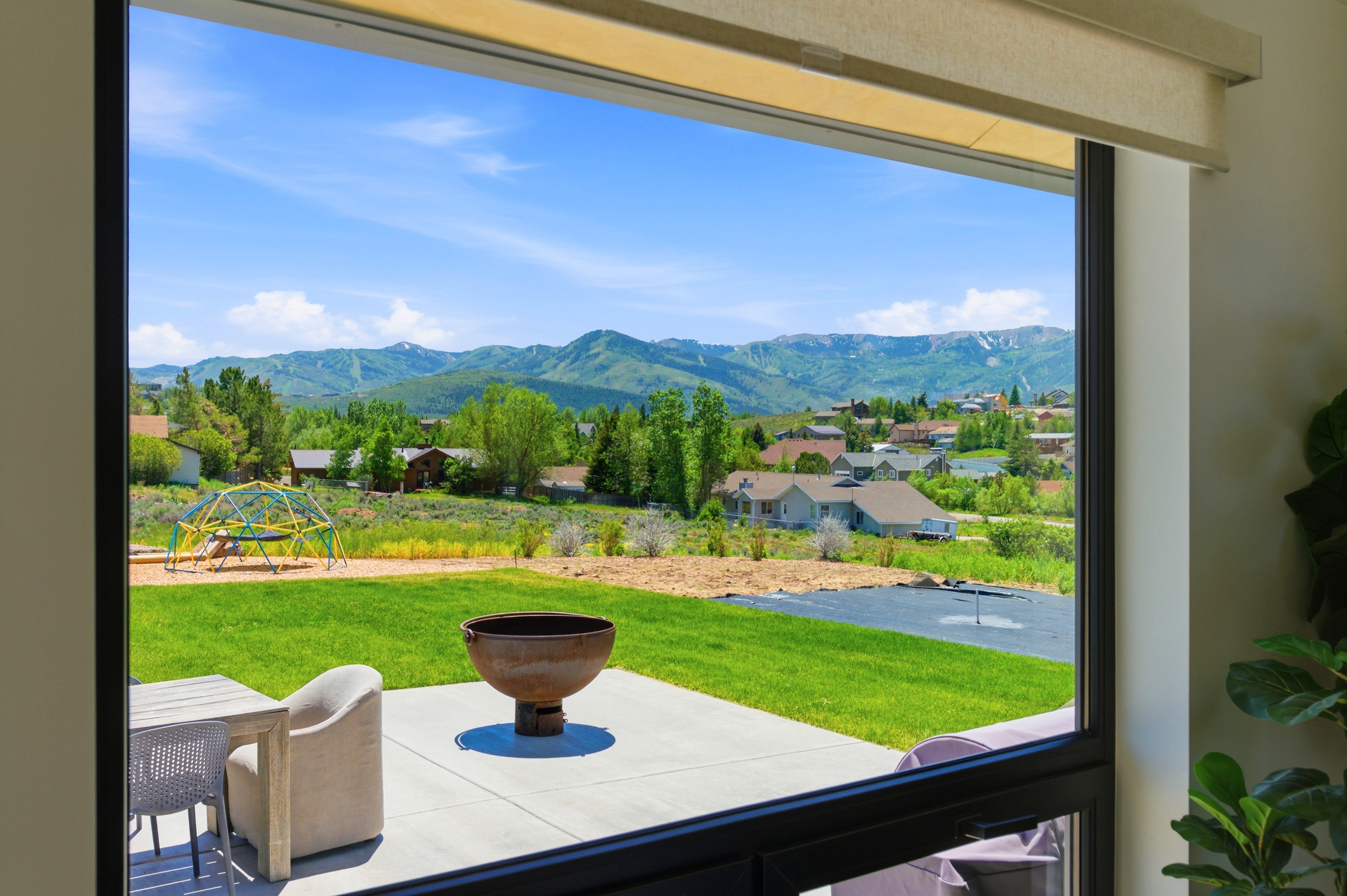 Expansive backyard with a manicured lawn and concrete patio, featuring a built-in fire pit
