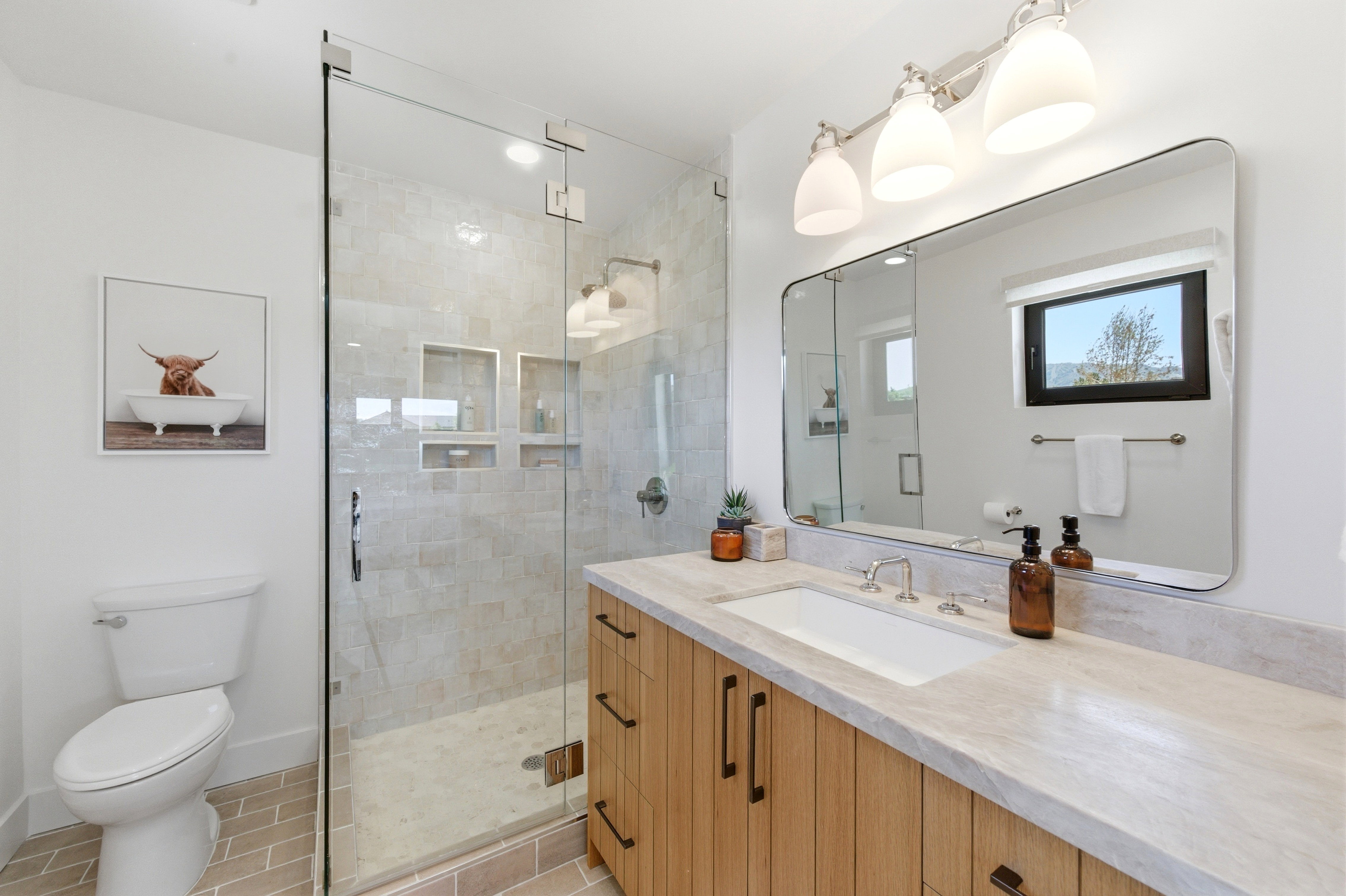 Modern bathroom featuring a glass-enclosed shower with tiled walls and multiple recessed shelves