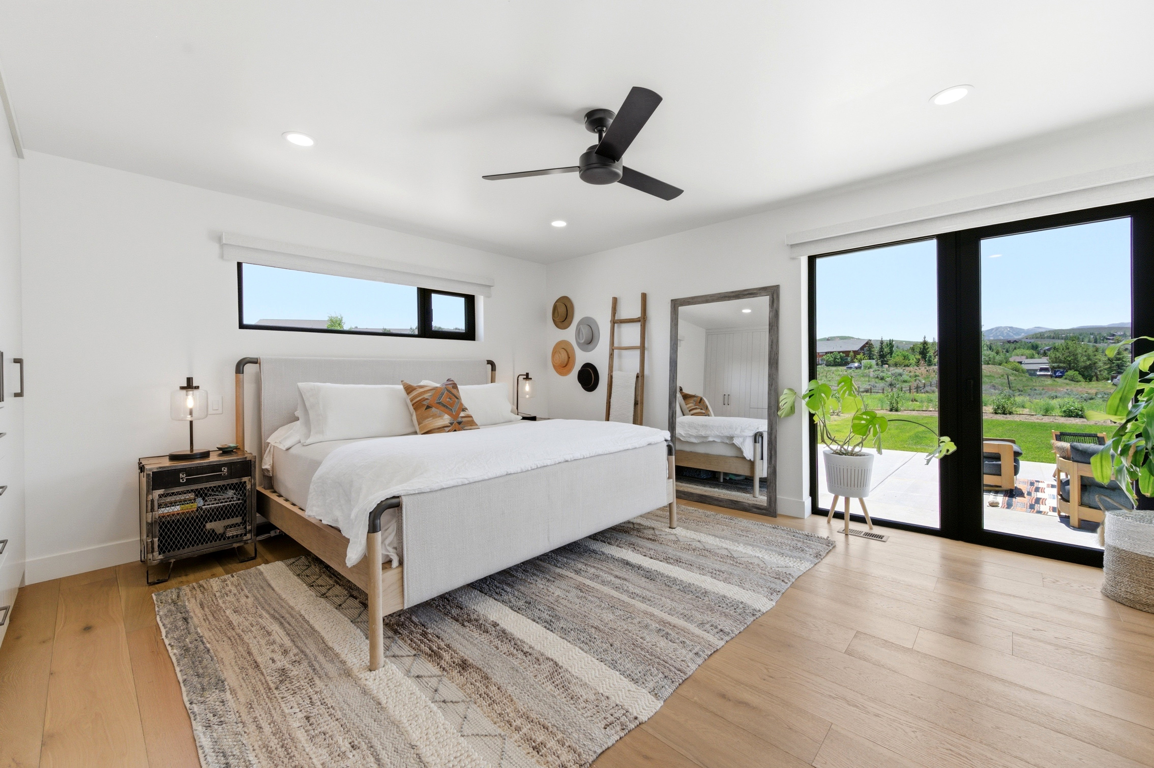 Light wood-finish flooring complements white walls and a black ceiling fan