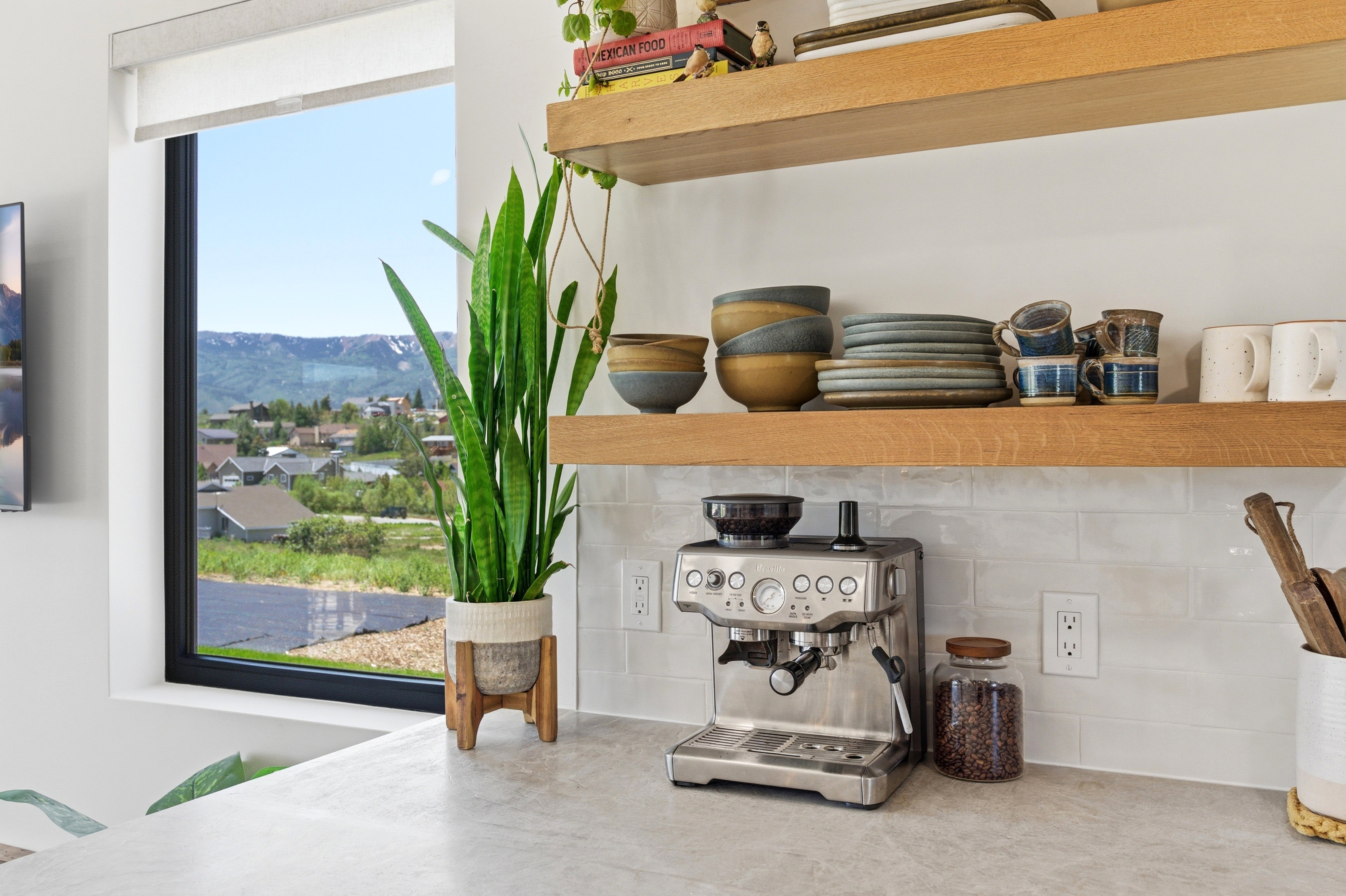 Kitchen counter featuring a light-colored countertop, white subway tile backsplash, and open wood shelving