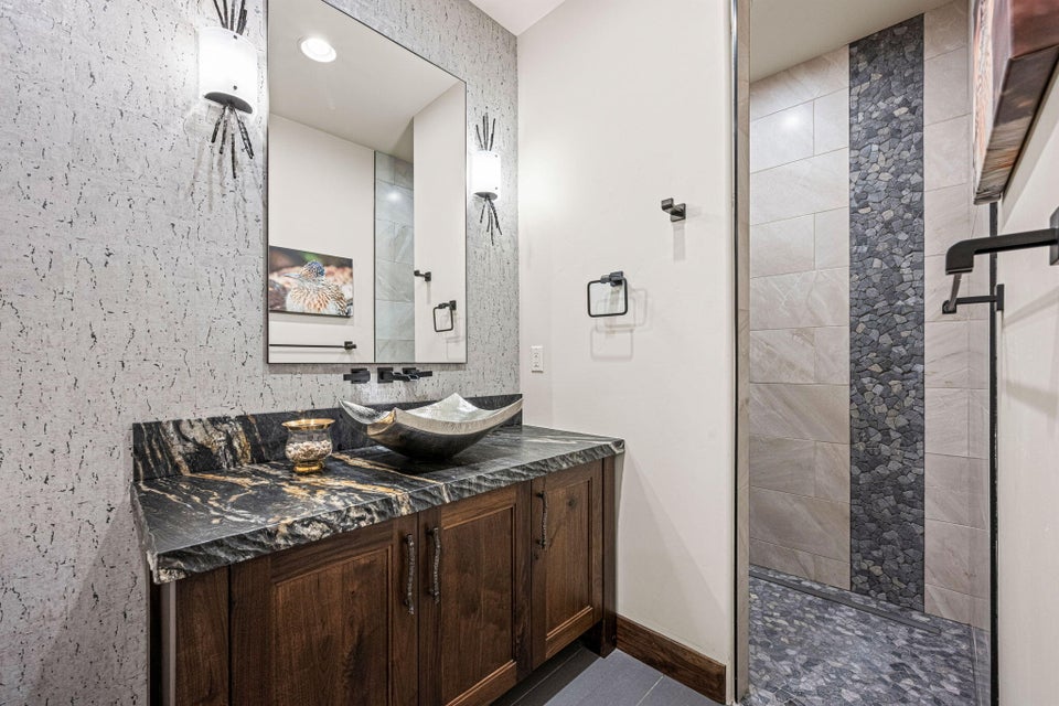 Bathroom featuring a dark wood-finish vanity with a dark granite countertop and vessel sink