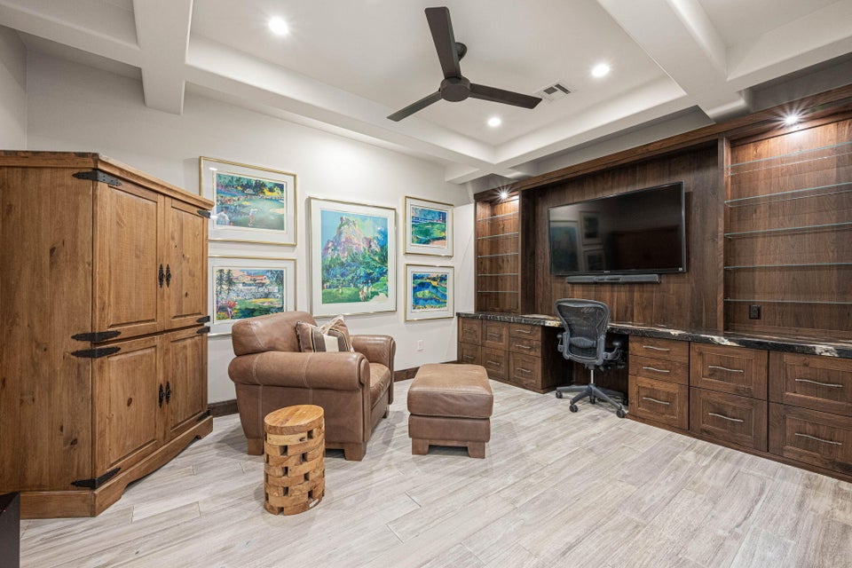 Built-in wood cabinetry with integrated desk space and shelving, under-cabinet lighting, and a dark stone countertop